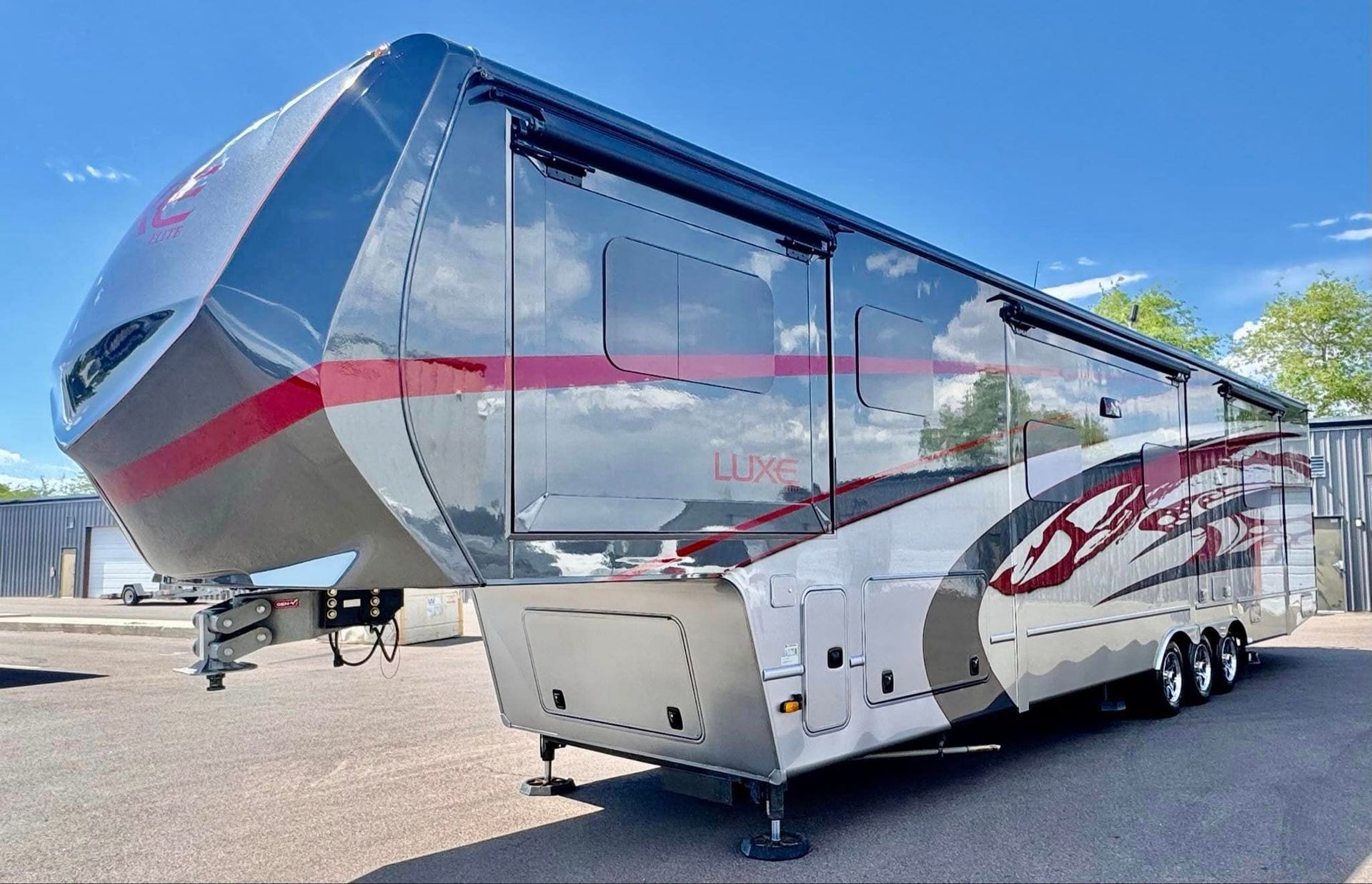 A large silver and red rv is parked in a parking lot with Bob Moses ceramic coating, Sensha World Crystal Glow