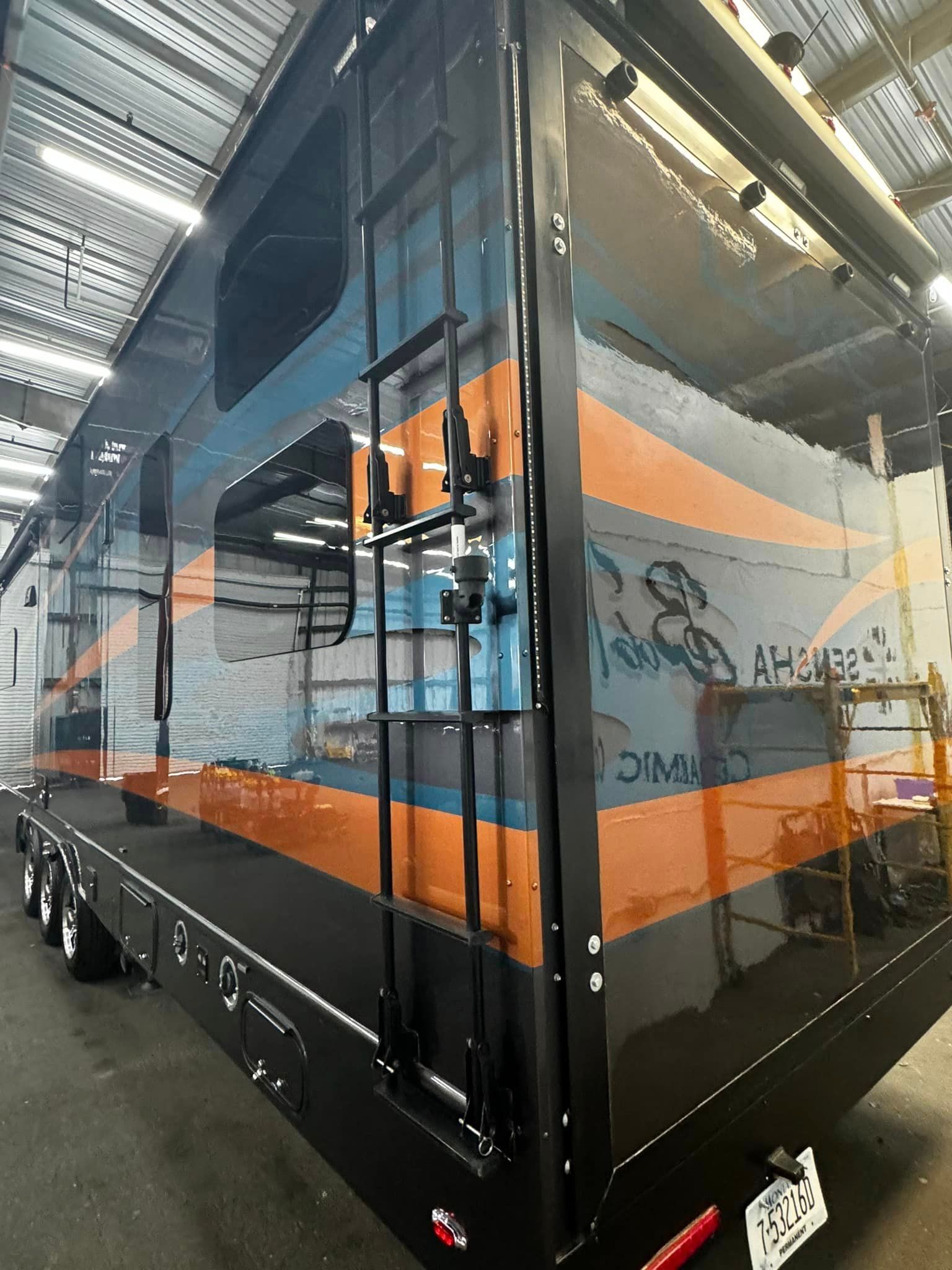 A blue and orange trailer is parked in a garage with Bob Moses ceramic coating, Sensha World Crystal Glow