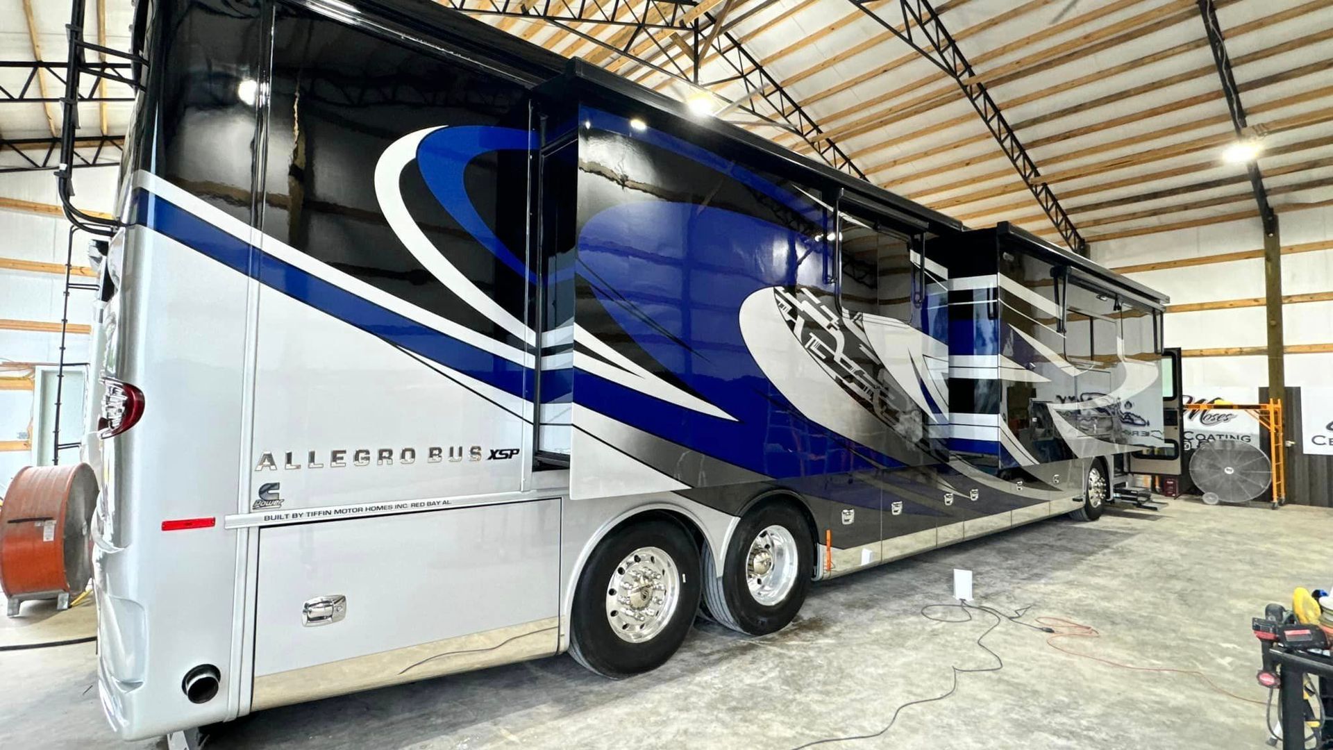 A large blue and white rv is parked in a garage with Bob Moses ceramic coating, Sensha World Crystal Glow