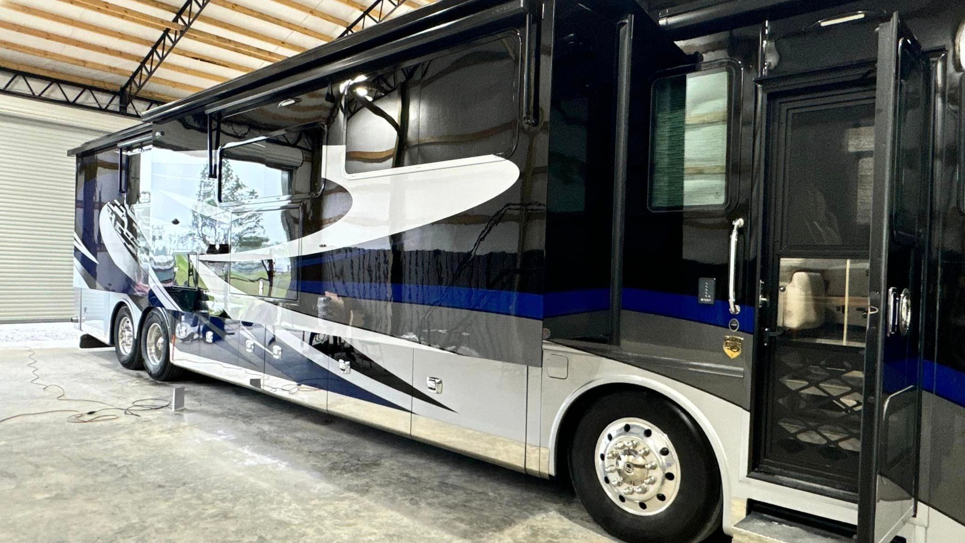 A large rv is parked in a garage with the door open with Bob Moses ceramic coating, Sensha World Crystal Glow