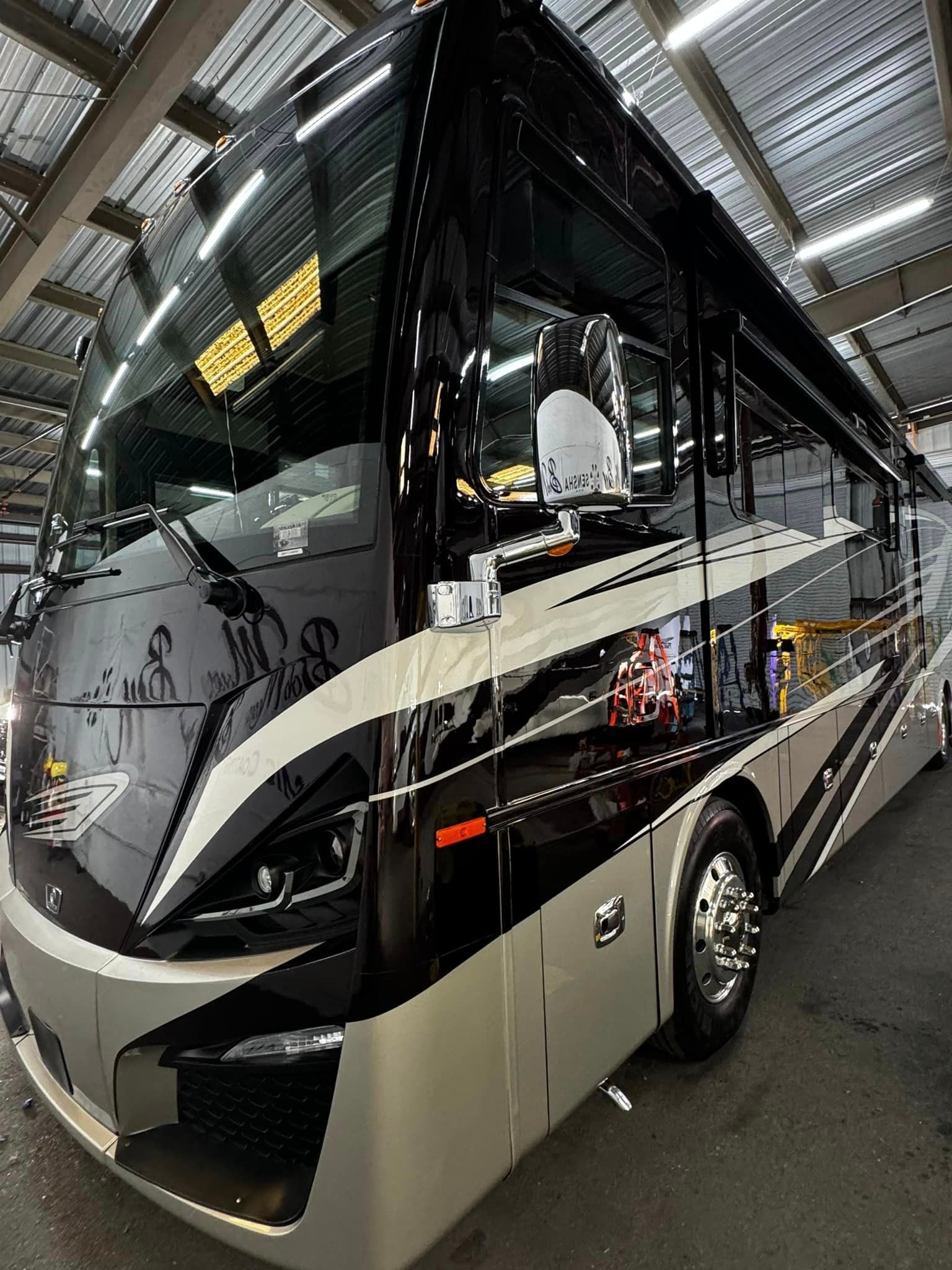 A large bus is parked in a garage with Bob Moses ceramic coating, Sensha World Crystal Glow