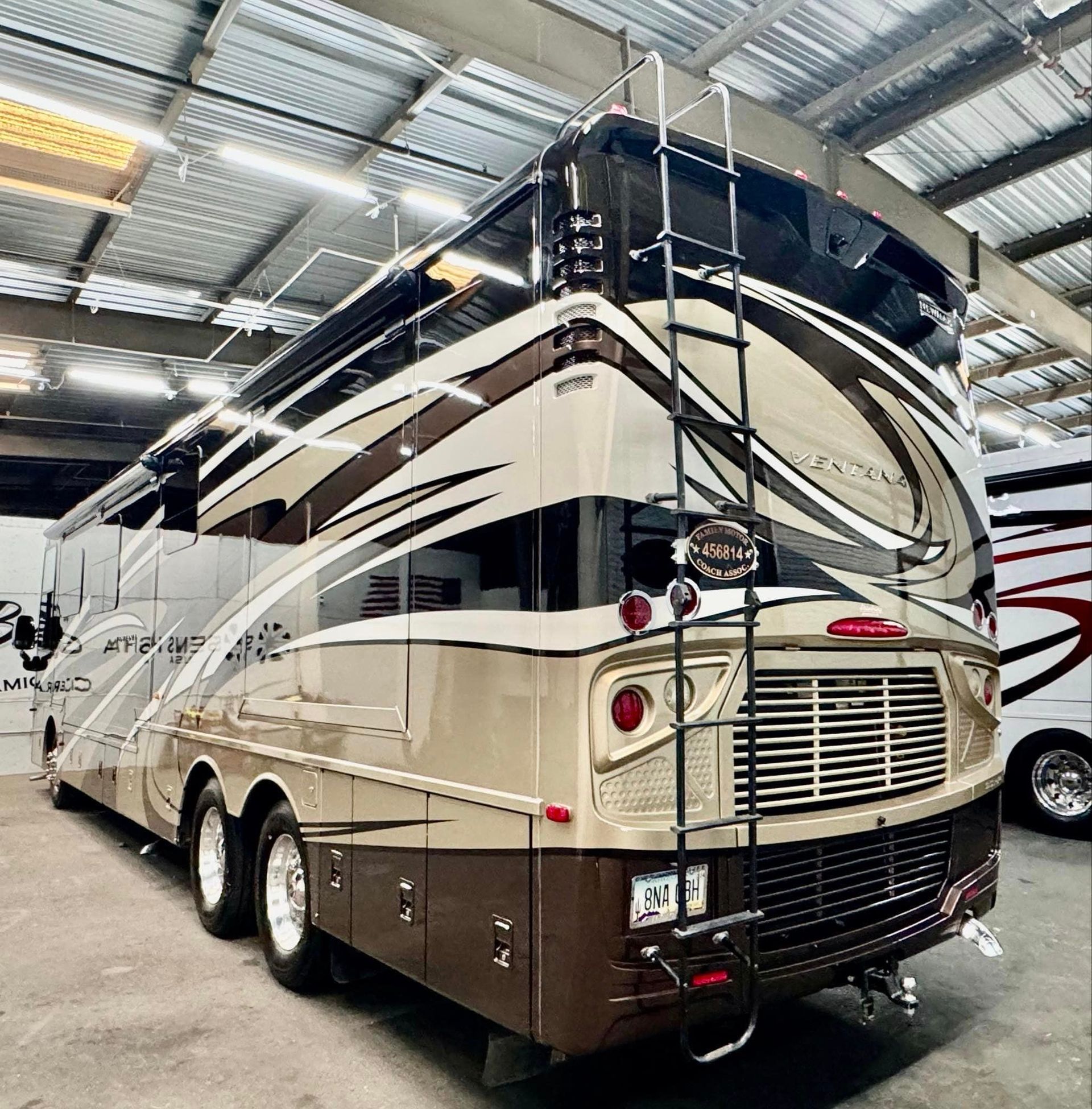 A large double decker rv is parked in a warehouse with Bob Moses ceramic coating, Sensha World Crystal Glow