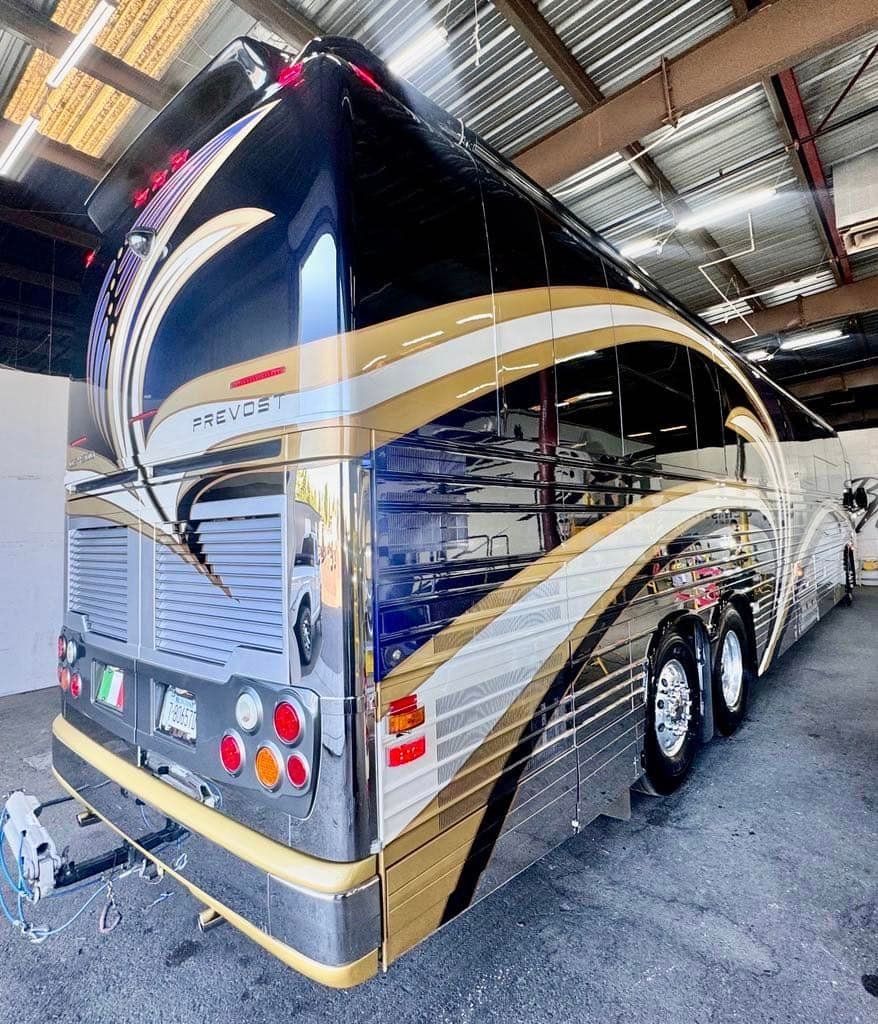 A large black and gold bus is parked in a garage with Bob Moses ceramic coating, Sensha World Crystal Glow