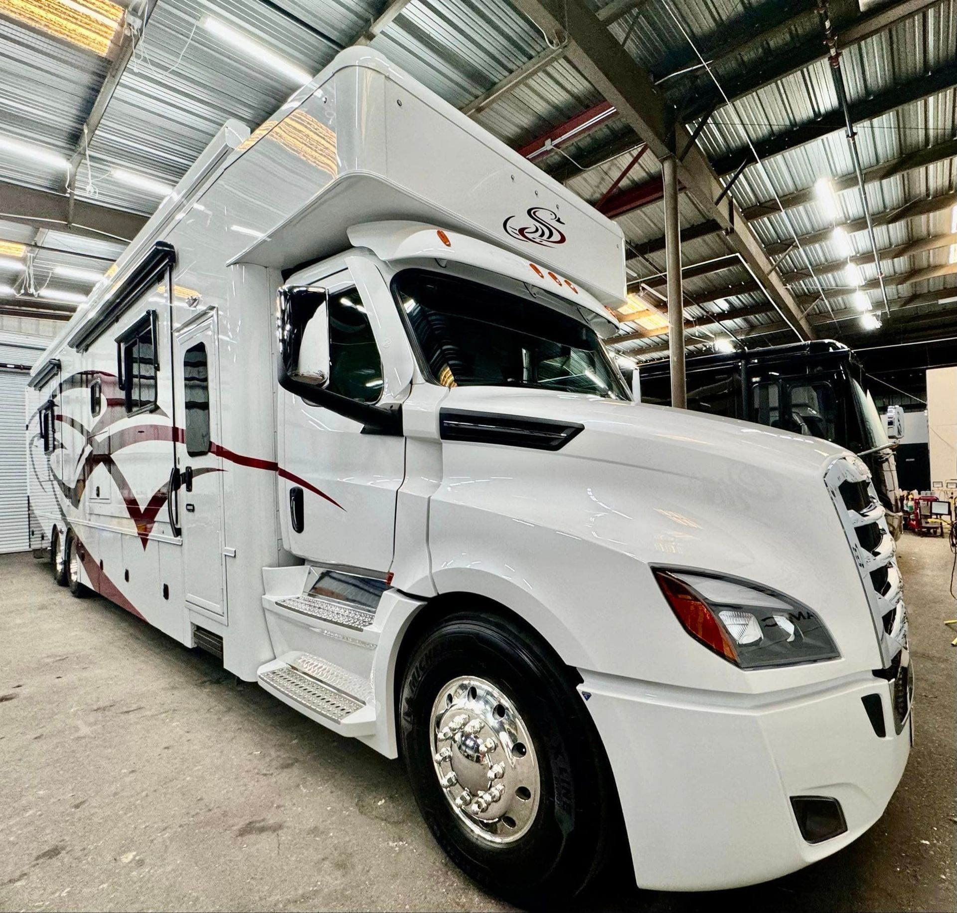 A large white rv is parked in a warehouse with Bob Moses ceramic coating, Sensha World Crystal Glow