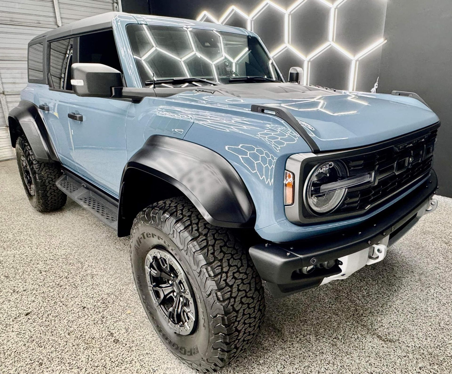 A blue ford bronco is parked in front of a building.