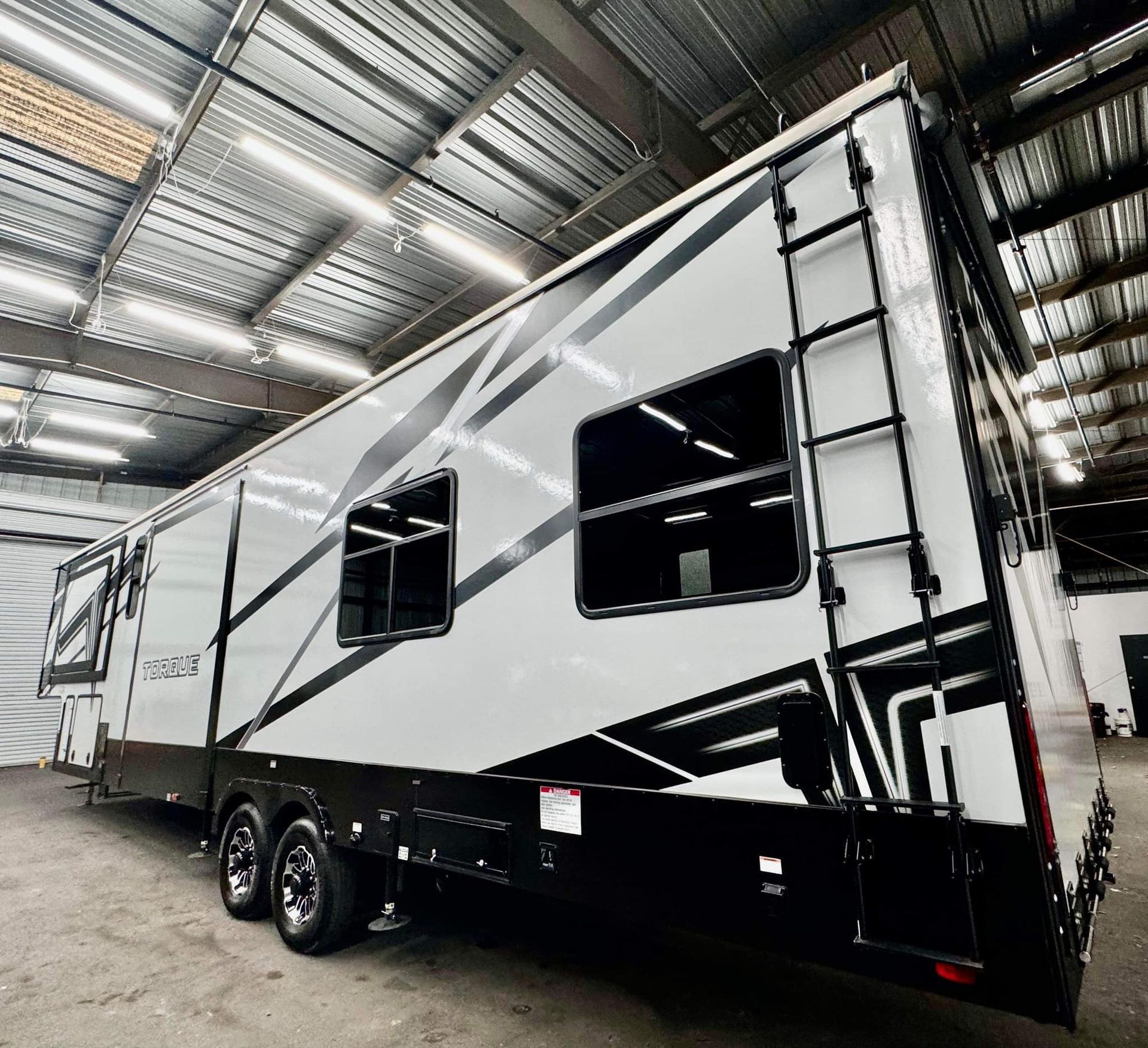 A white and black trailer is parked in a warehouse with Bob Moses ceramic coating, Sensha World Crystal Glow