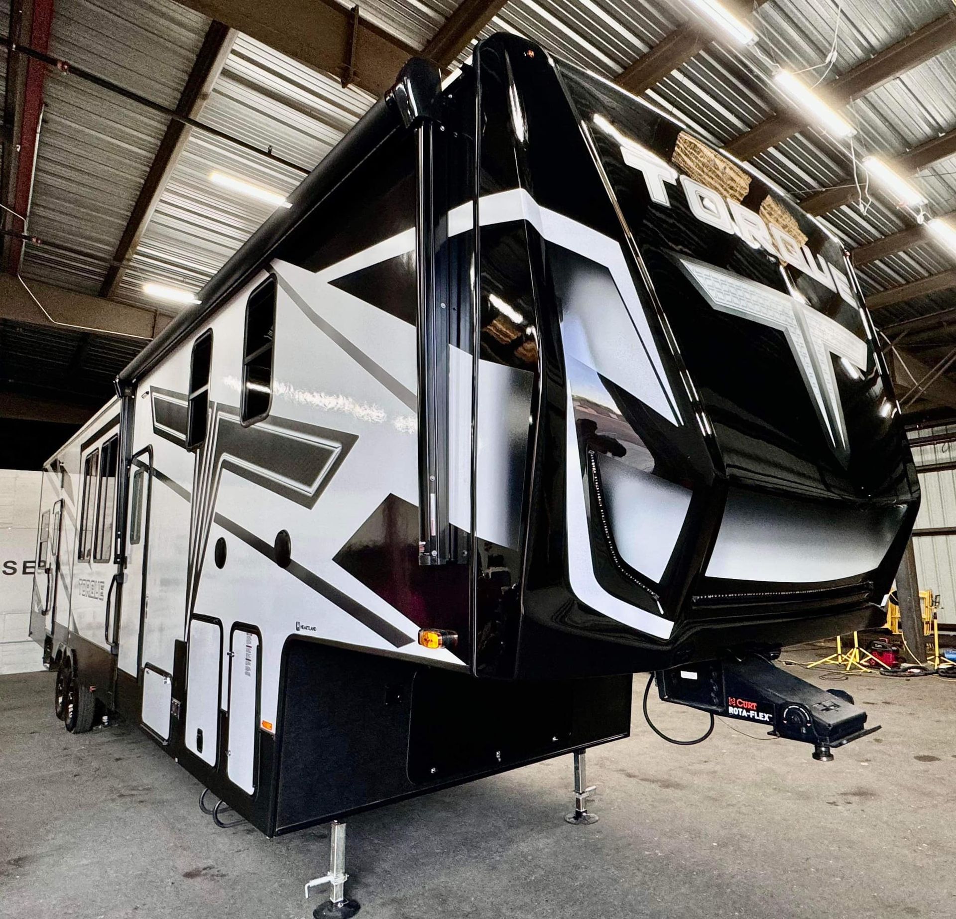 A black and white trailer is parked in a warehouse with Bob Moses ceramic coating, Sensha World Crystal Glow