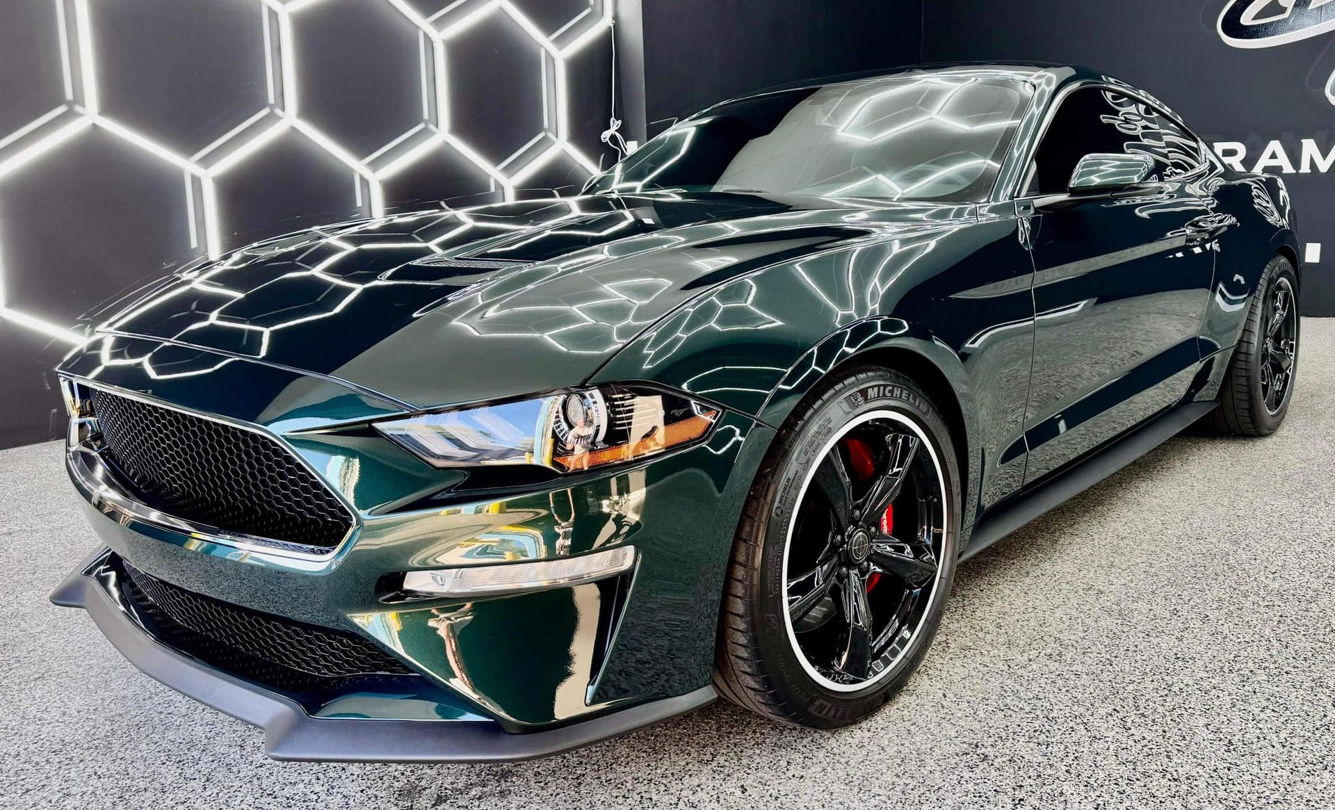 A green ford mustang is parked in a showroom with Bob Moses ceramic coating, Sensha World Crystal Glow