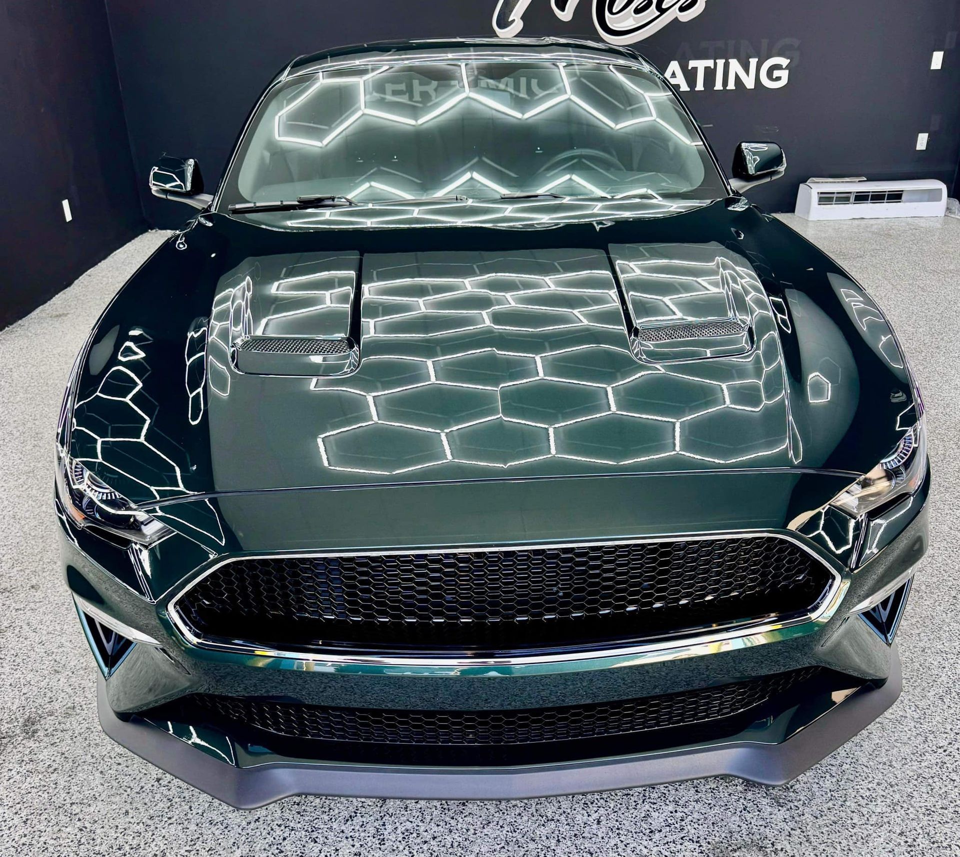A green ford mustang is parked in a garage with Bob Moses ceramic coating, Sensha World Crystal Glow