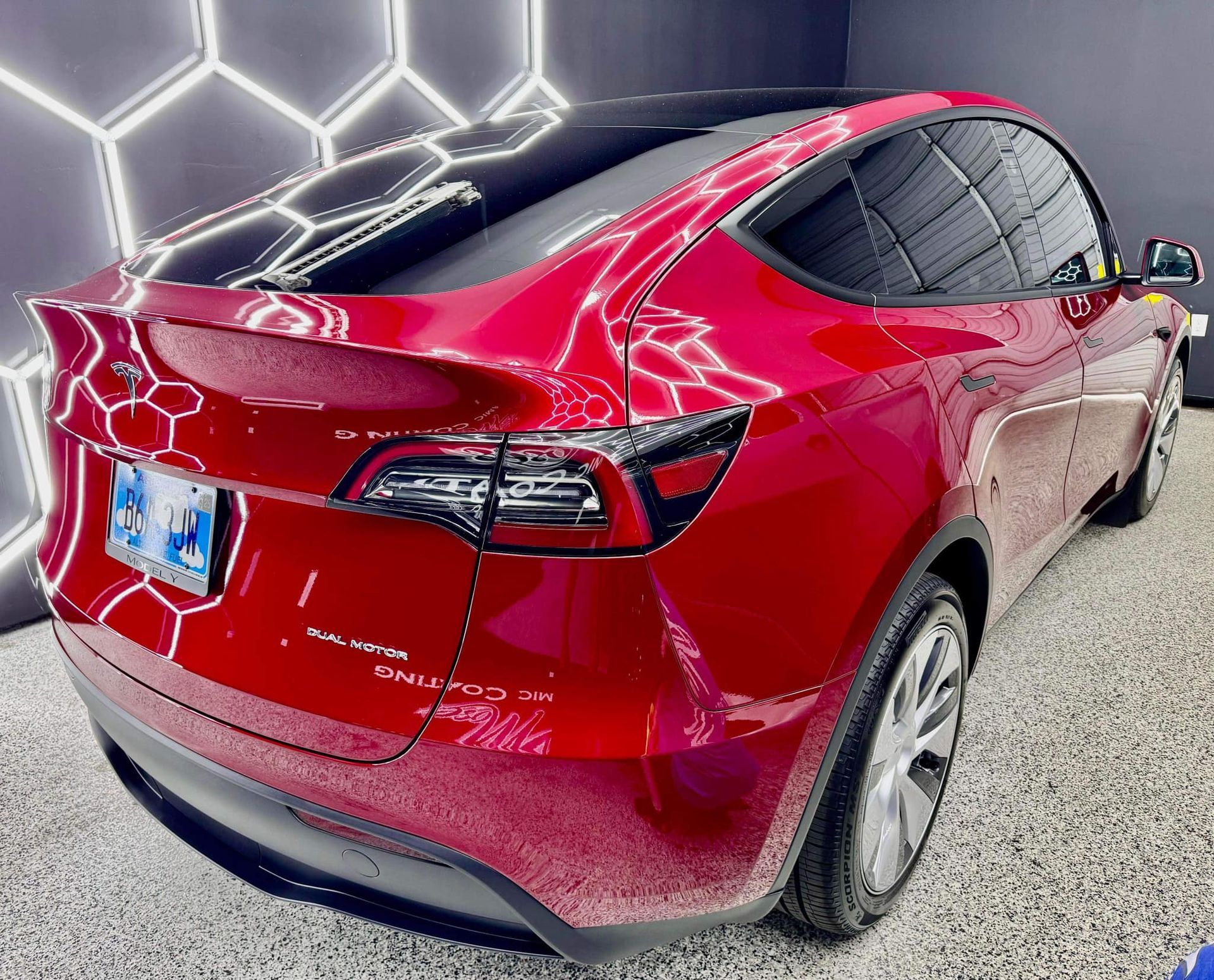 A red tesla model y is parked in a garage.