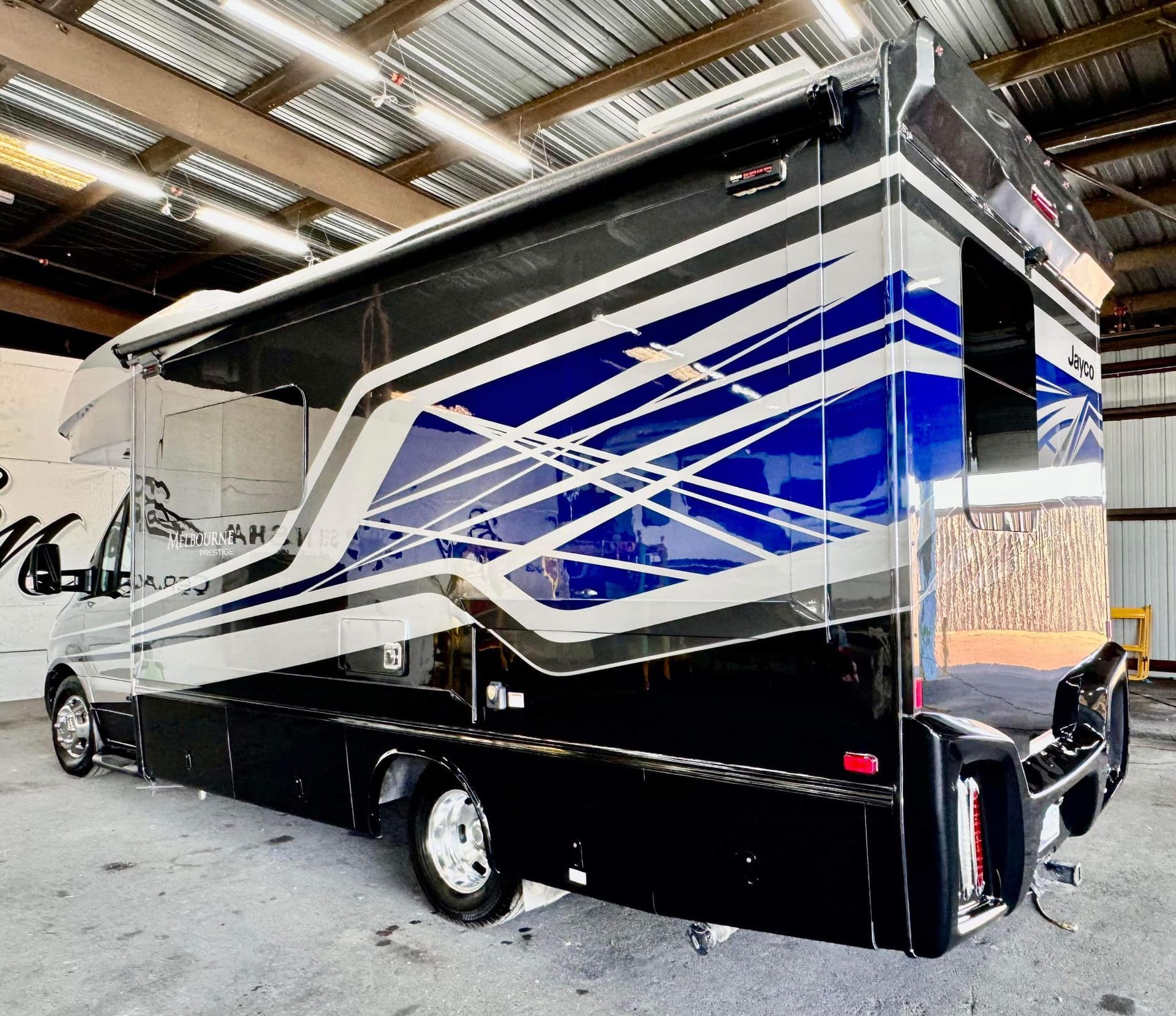 A blue and black rv is parked in a garage with Bob Moses ceramic coating, Sensha World Crystal Glow