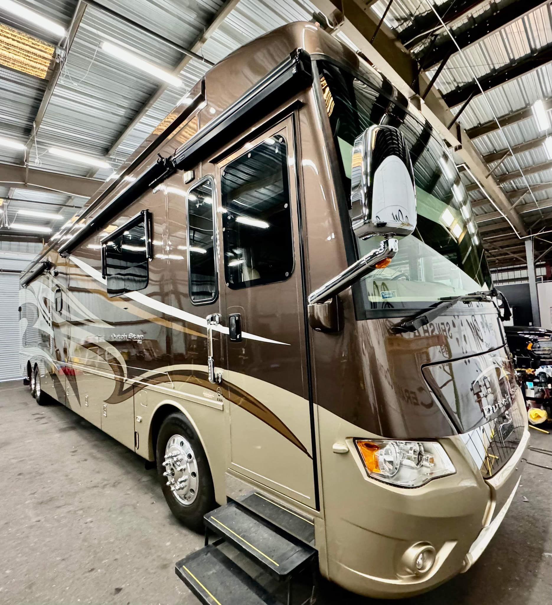 A large brown and tan rv is parked in a garage with Bob Moses ceramic coating, Sensha World Crystal Glow