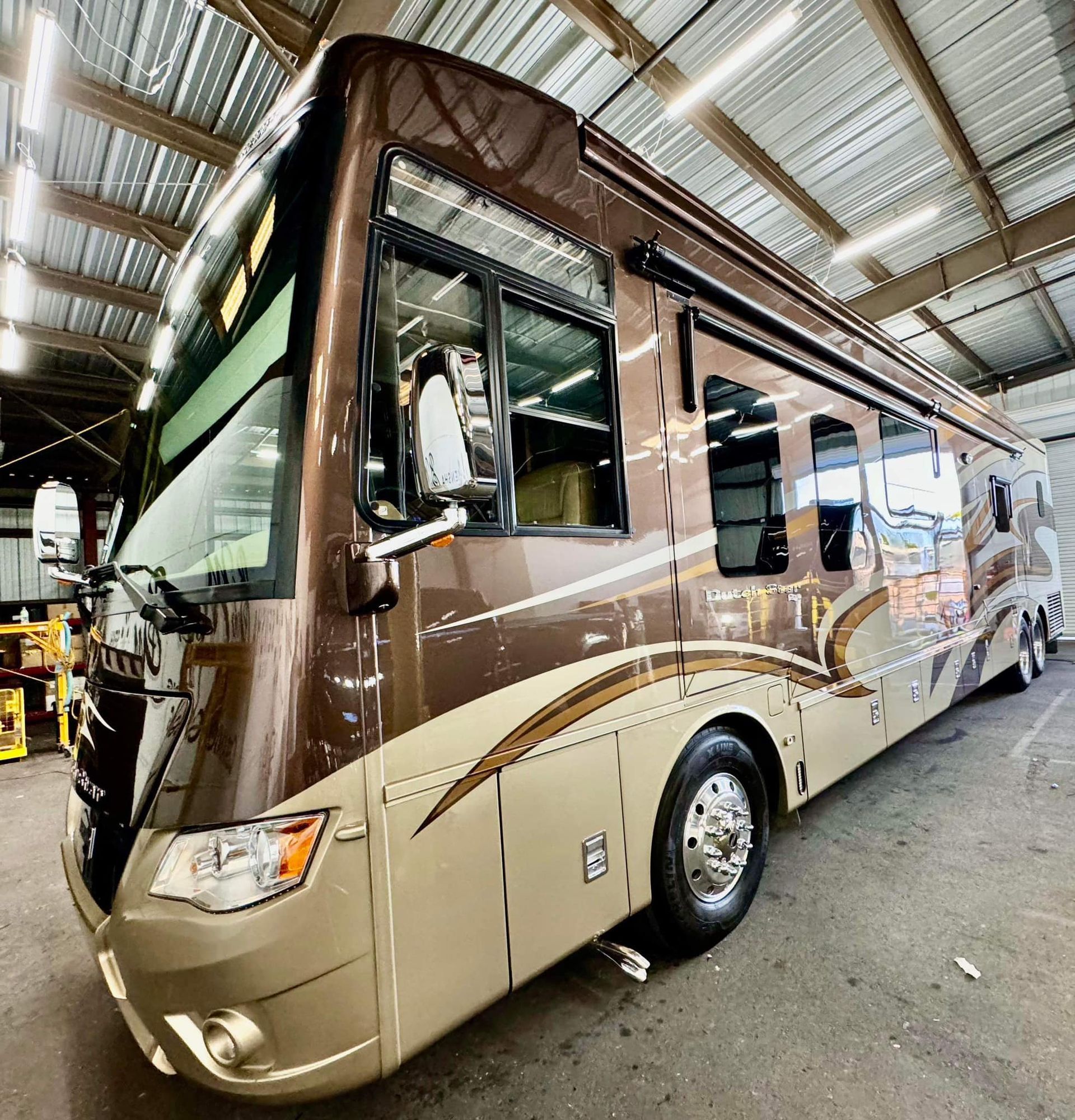 A large brown and tan rv is parked in a garage with Bob Moses ceramic coating, Sensha World Crystal Glow