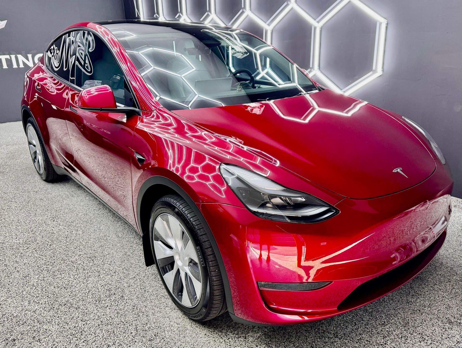 A red tesla model y is parked in a garage.