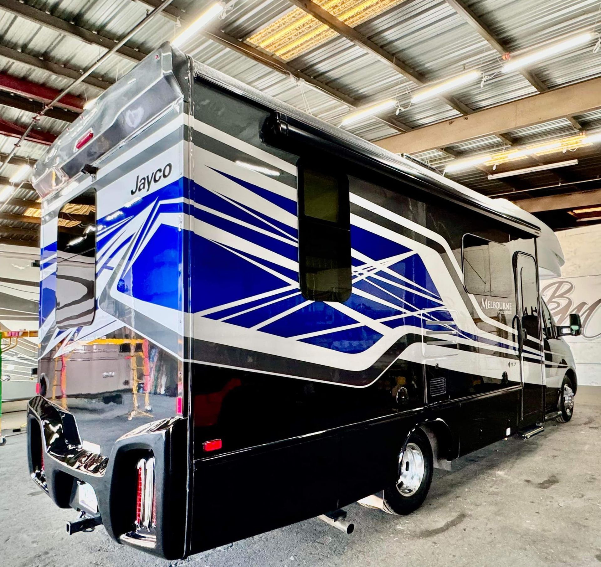 A blue and white rv is parked in a garage with Bob Moses ceramic coating, Sensha World Crystal Glow