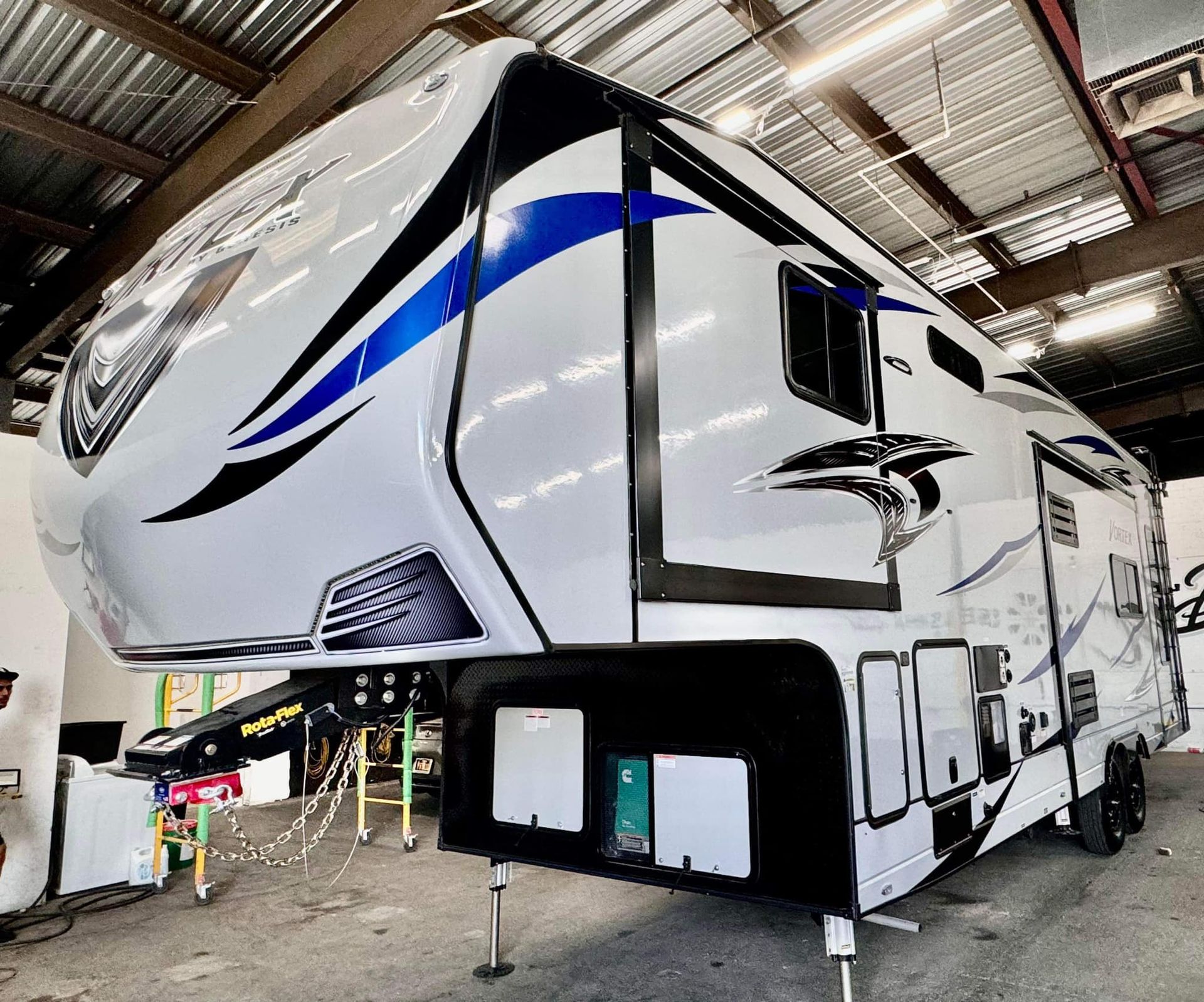 A white and blue rv is parked in a garage.