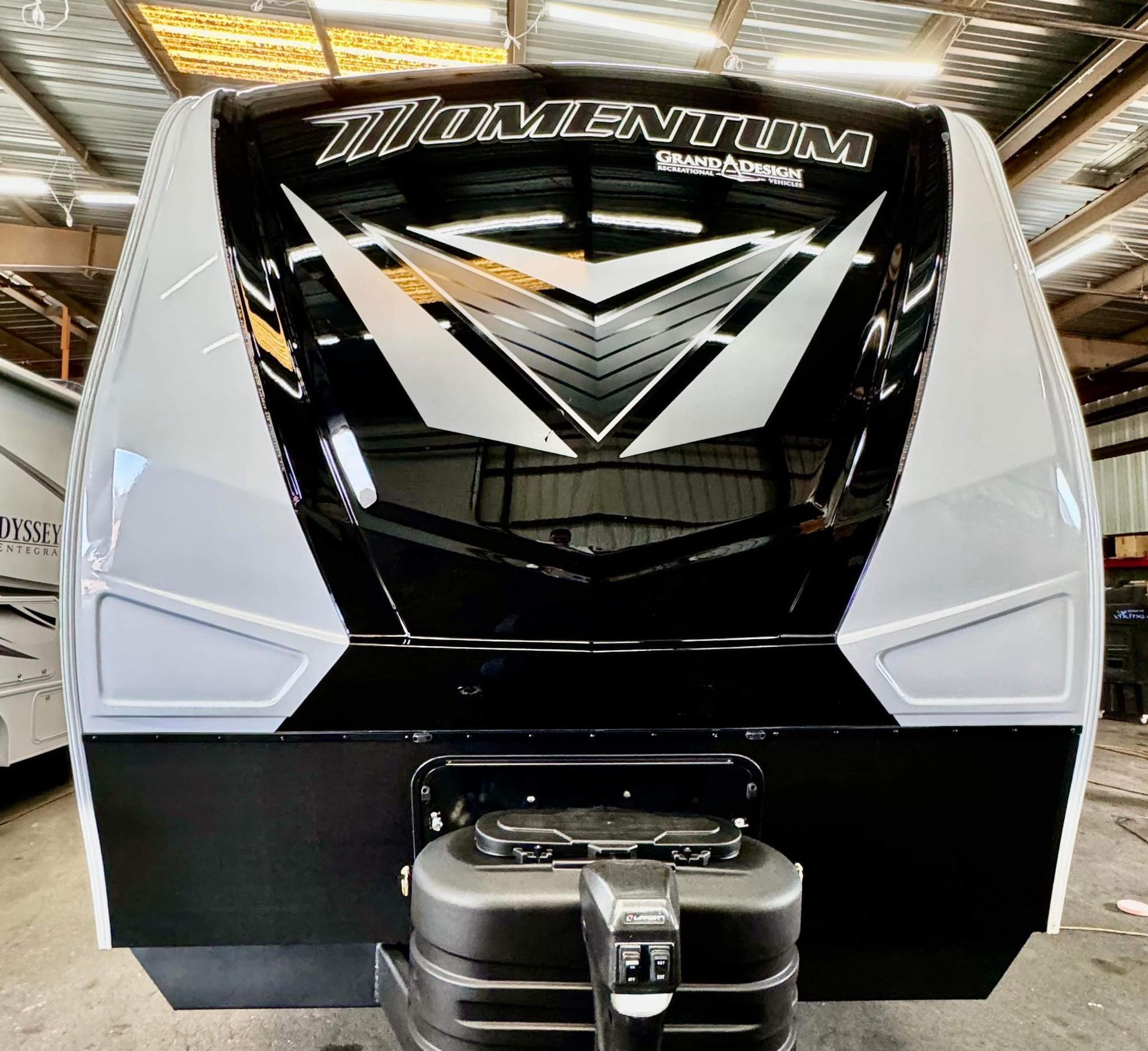 A black and white rv is parked in a warehouse.