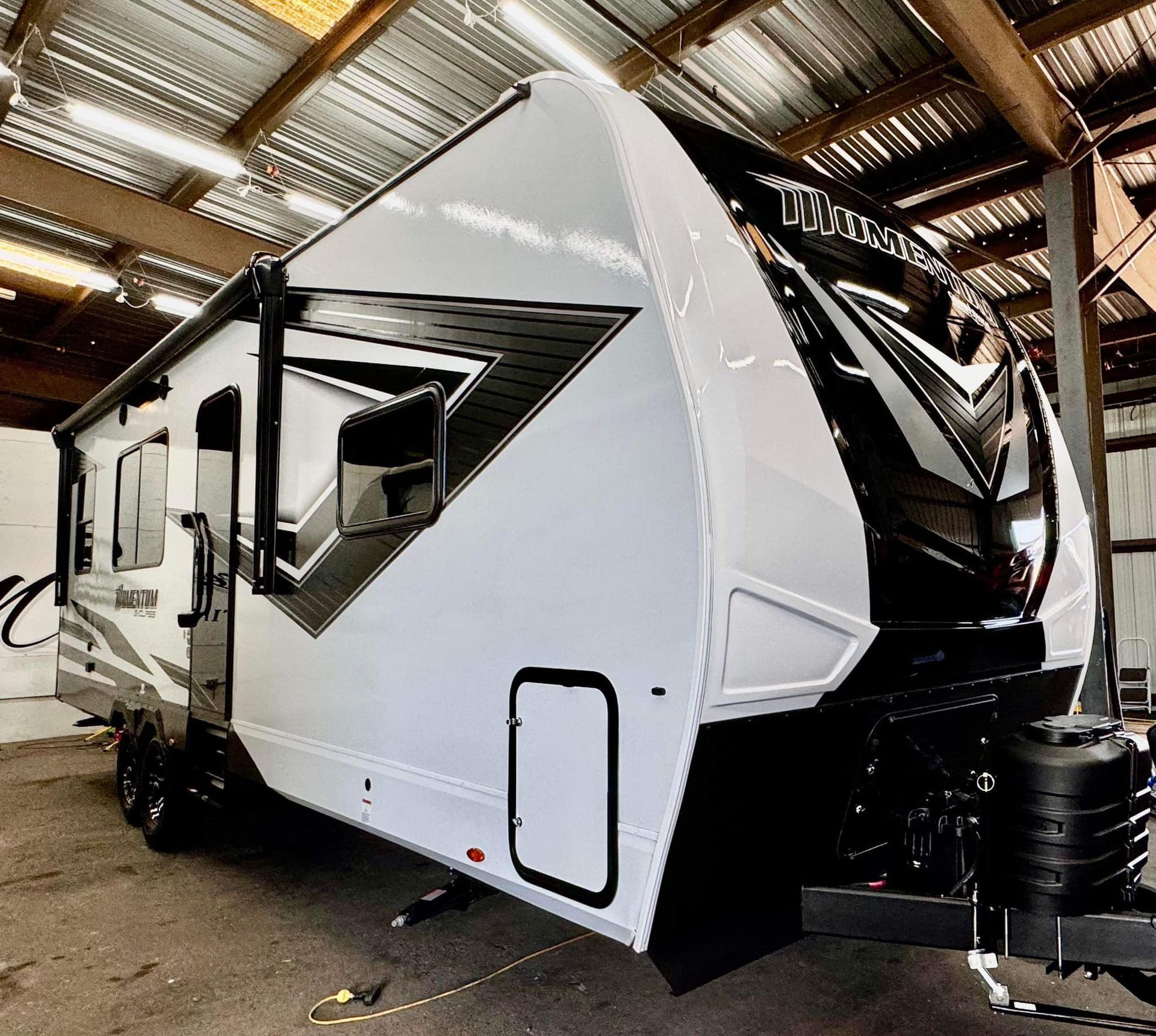 A white and black trailer is parked in a garage.