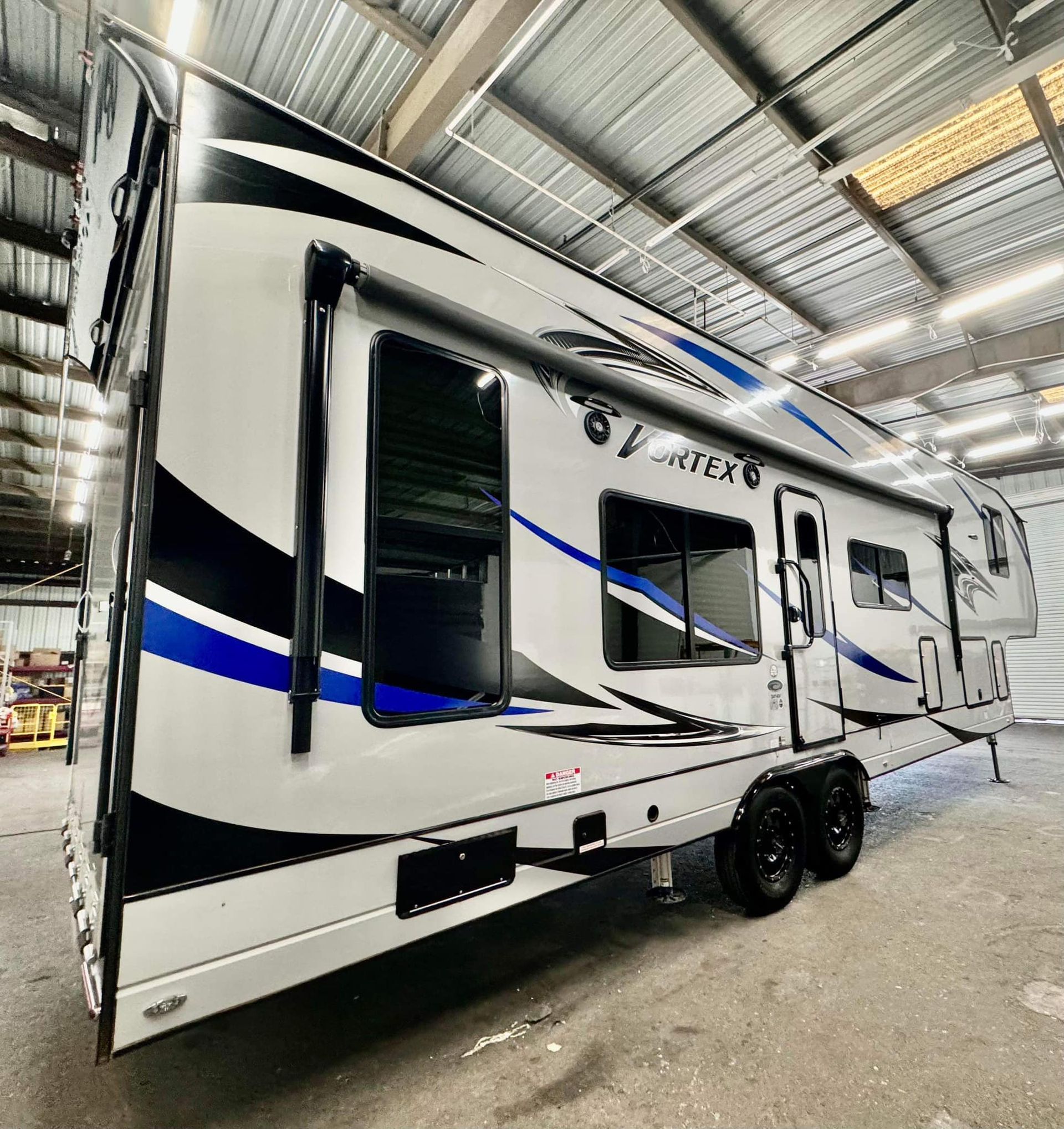 A white and blue trailer is parked in a warehouse.