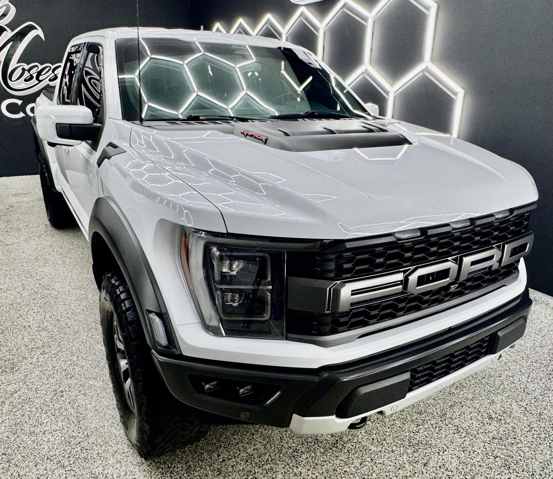 A white ford raptor truck is parked in a showroom with Bob Moses ceramic coating, Sensha World Crystal Glow