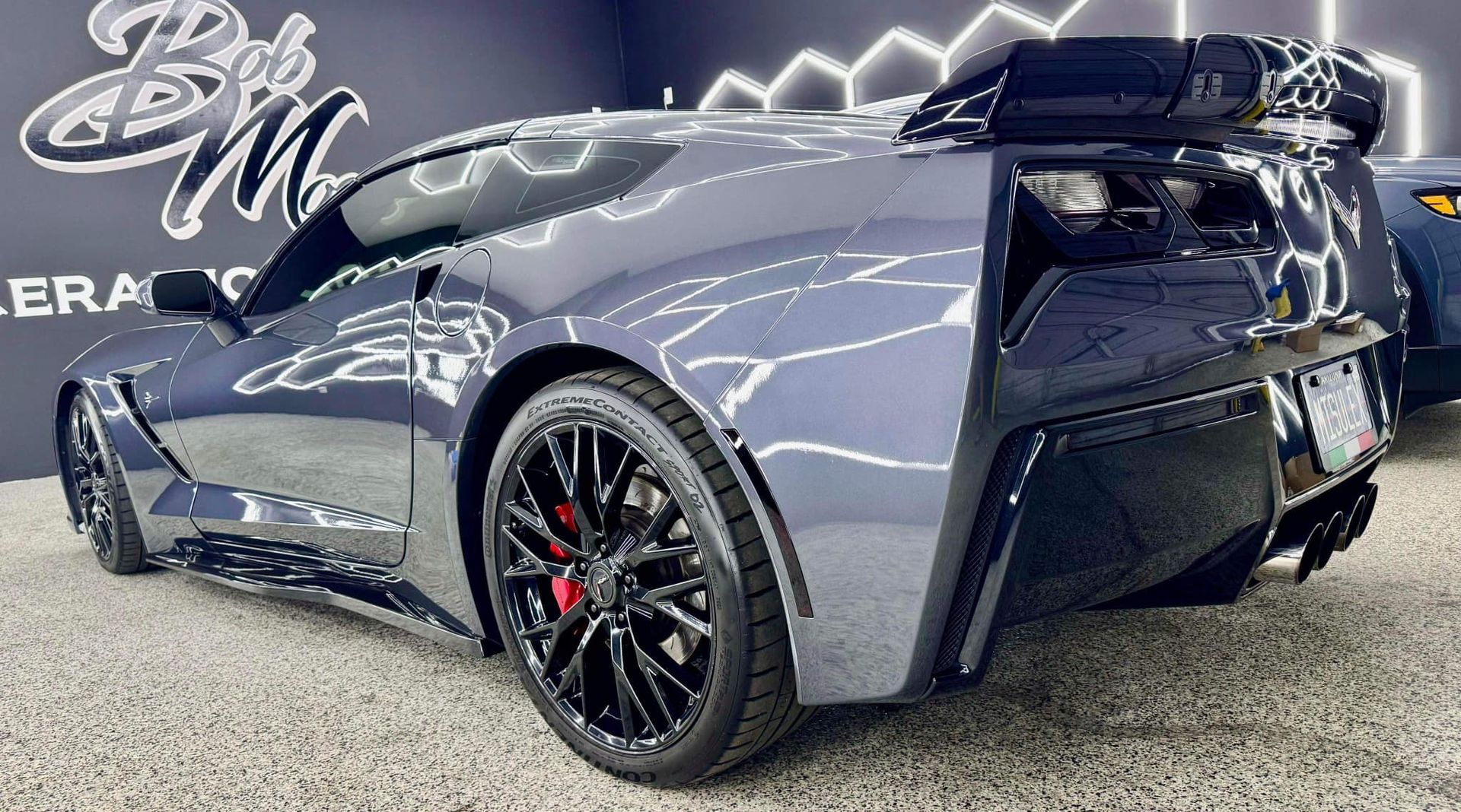 A black sports car is parked in a showroom with Bob Moses ceramic coating, Sensha World Crystal Glow