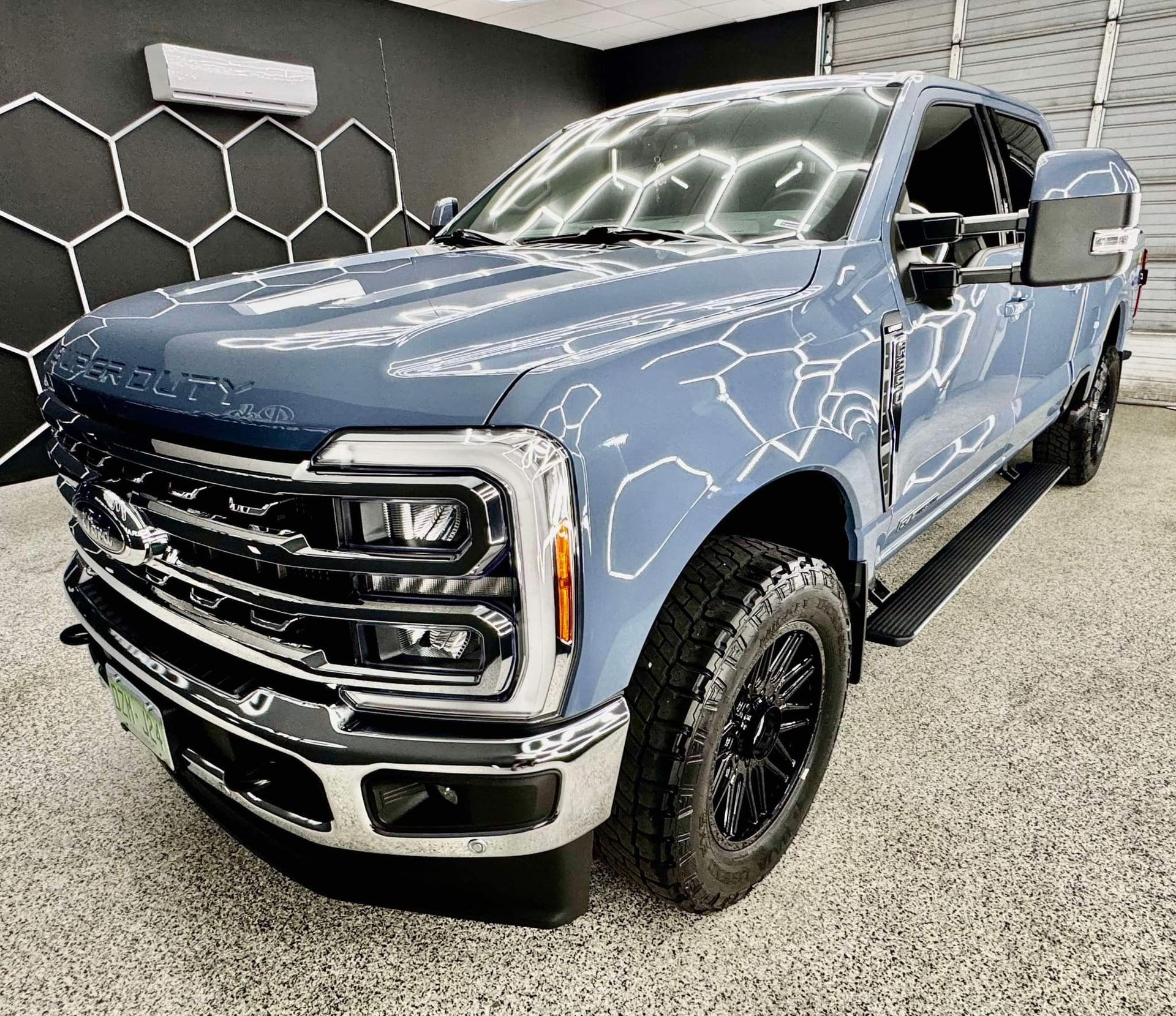 A blue ford f250 super duty truck is parked in a garage with Bob Moses ceramic coating, Sensha World Crystal Glow