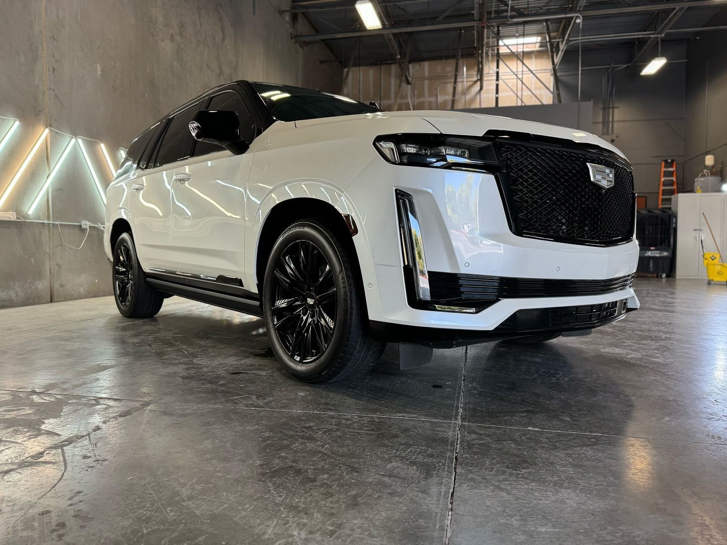 A white cadillac escalade is parked in a garage with Bob Moses ceramic coating, Sensha World Crystal Glow