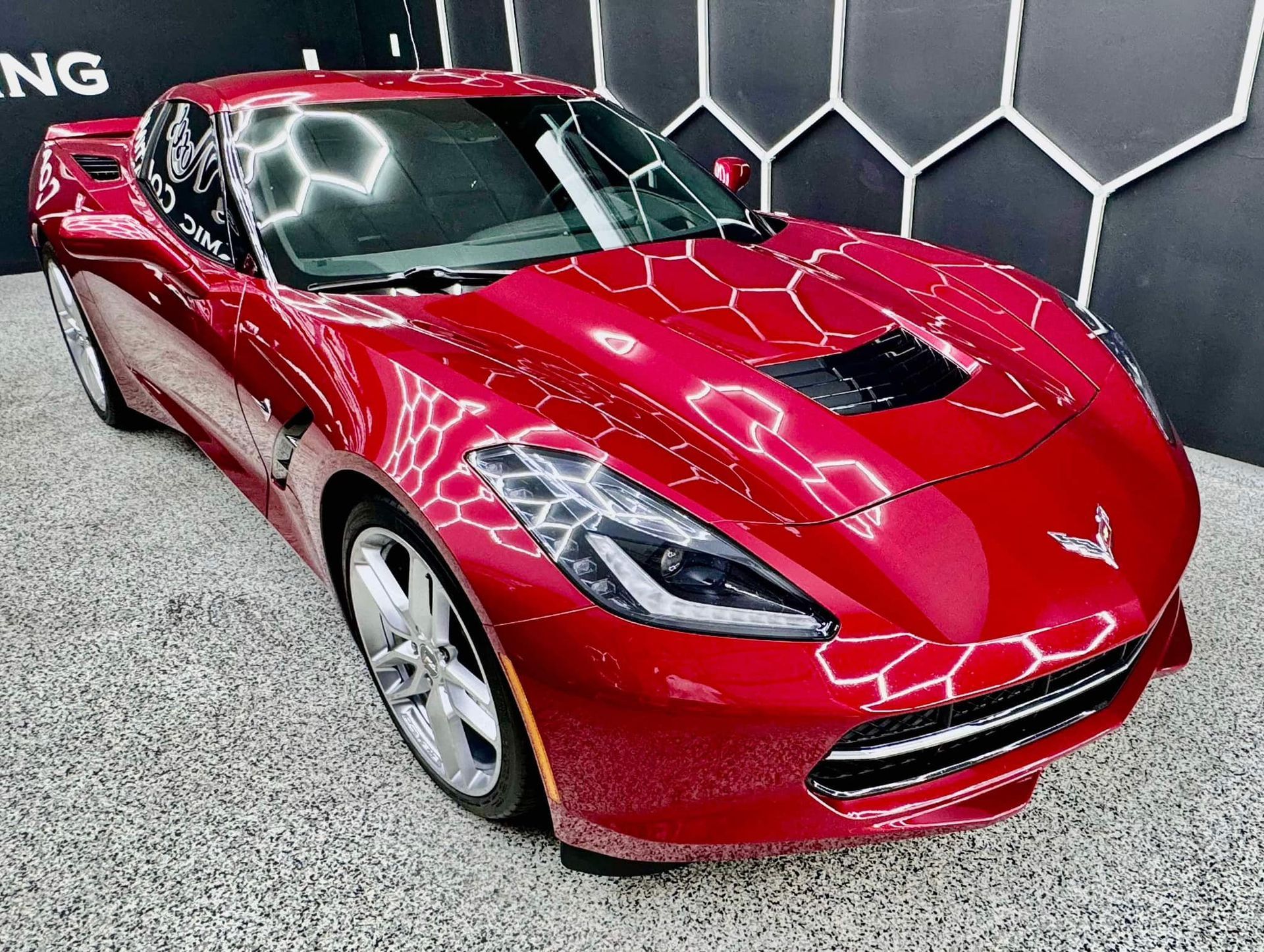 A red corvette is parked in a garage with Bob Moses ceramic coating, Sensha World Crystal Glow