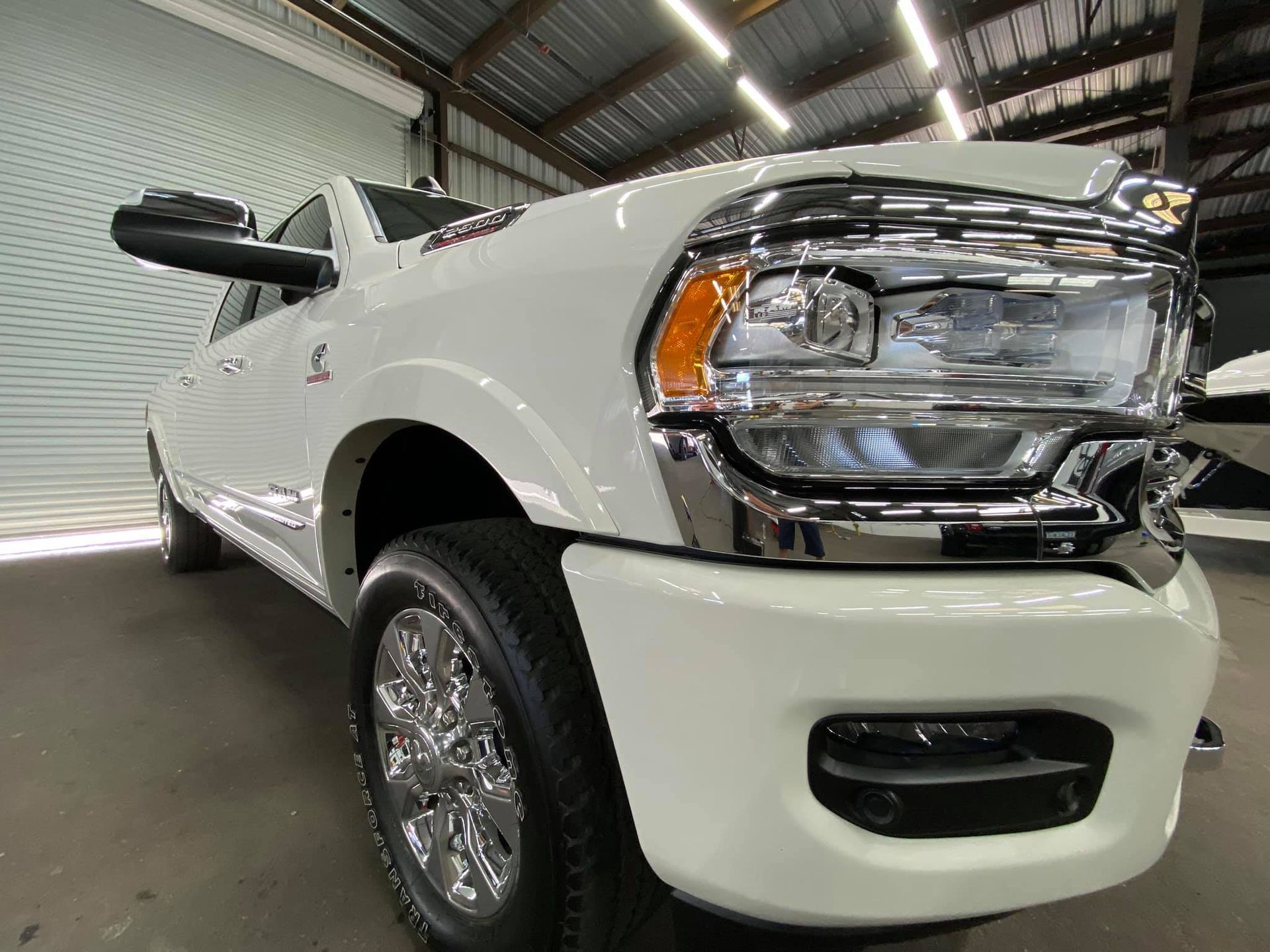 A white dodge ram truck is parked in a garage with Bob Moses ceramic coating, Sensha World Crystal Glow
