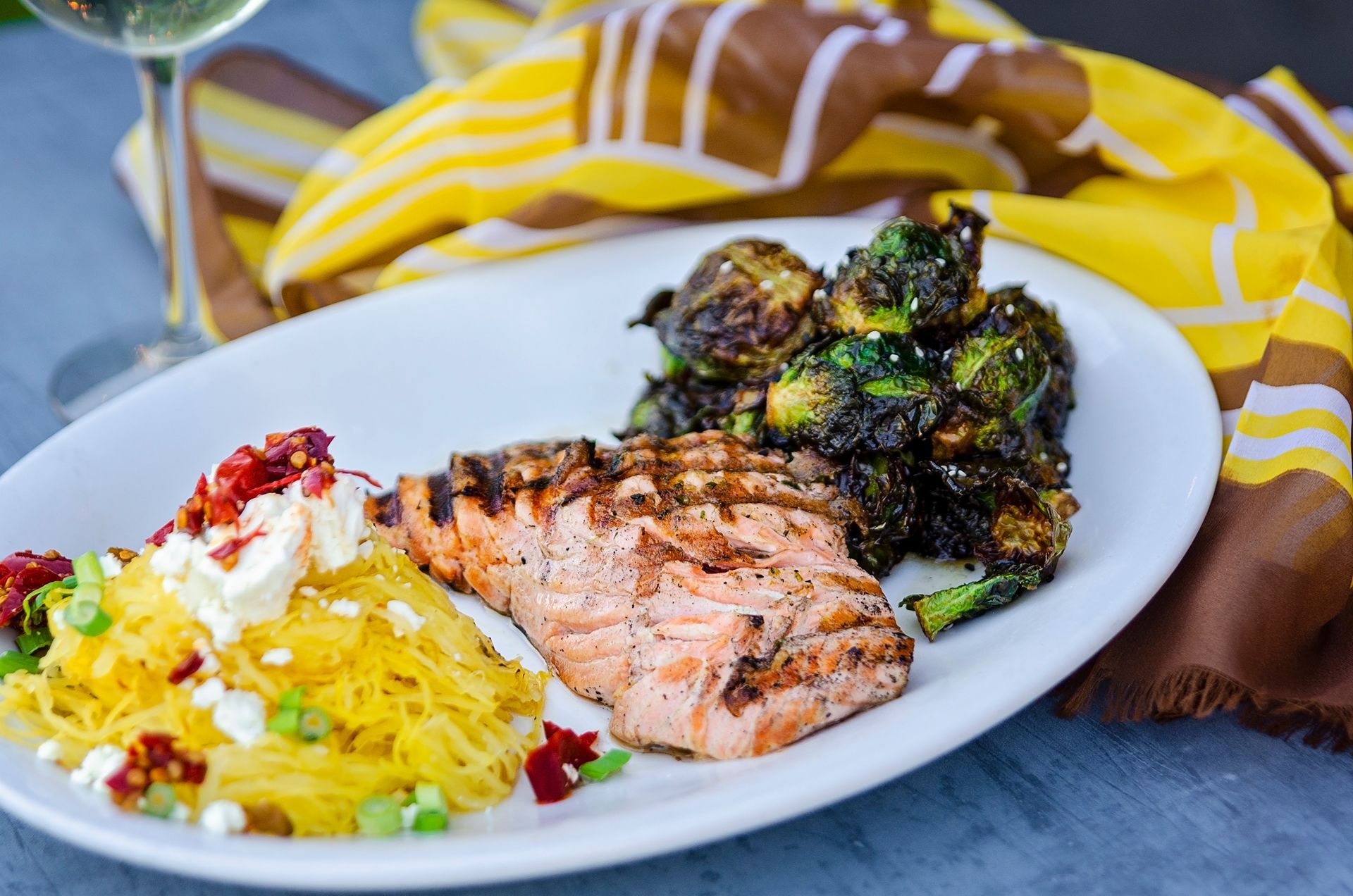A white plate topped with spaghetti squash, broccoli, and salmon.