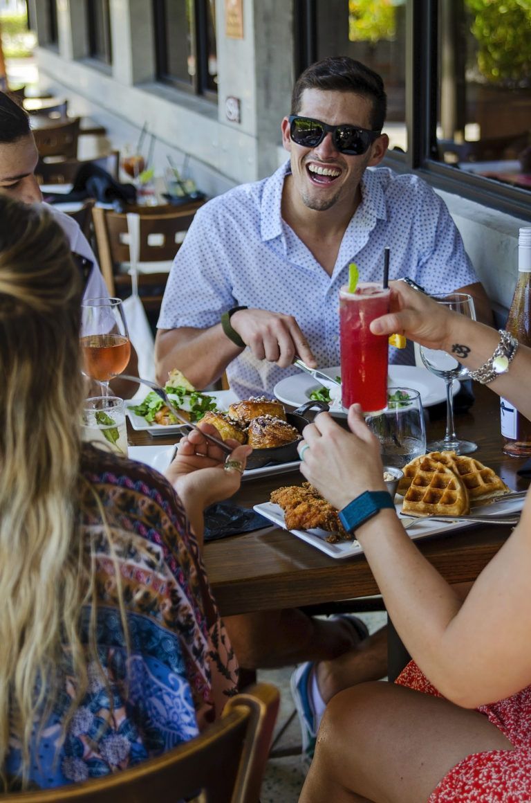 A group of people are sitting at a table eating food and drinking.