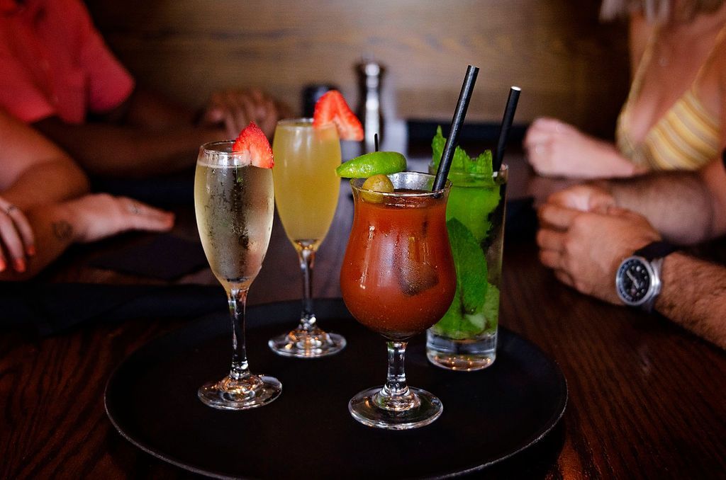 A group of people are sitting at a table with a tray of drinks on it.