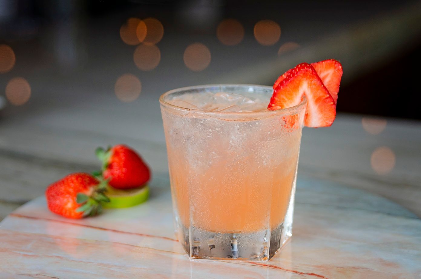 A close up of a drink with strawberries on a table.