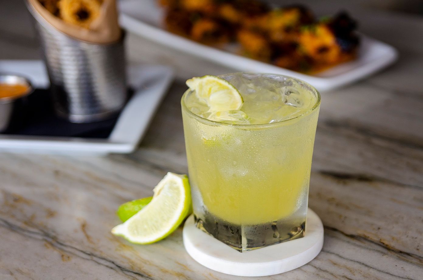A close up of a drink with a slice of lime on a table.