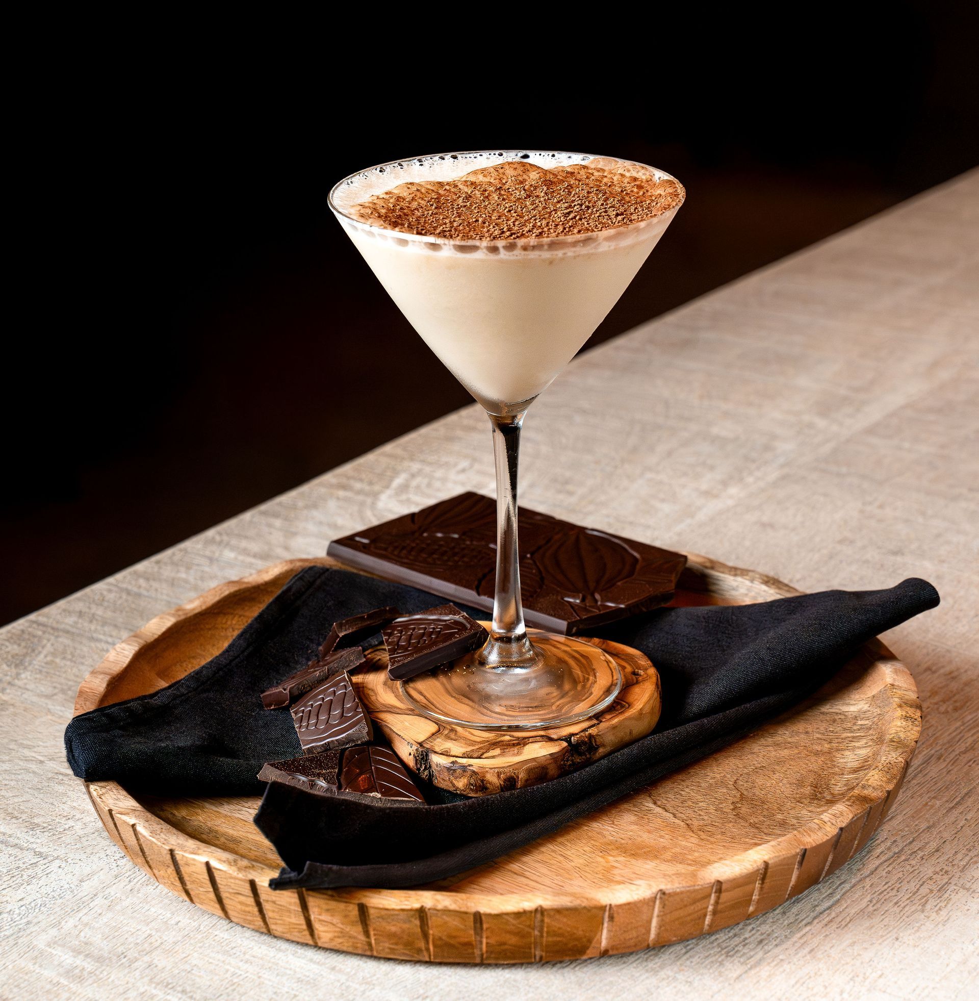 A martini glass sitting on top of a wooden tray.