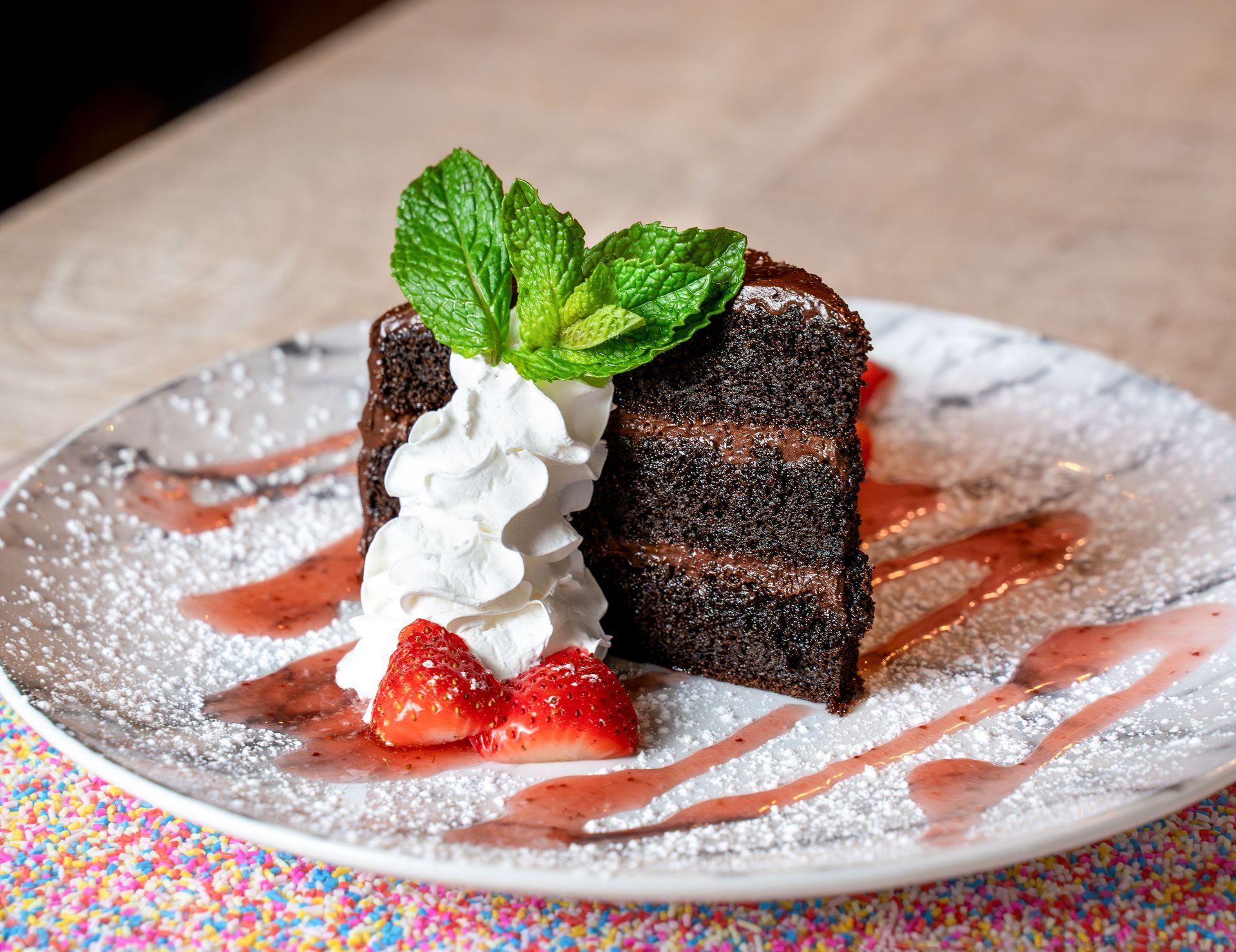 A slice of chocolate cake with whipped cream and strawberries on a plate.