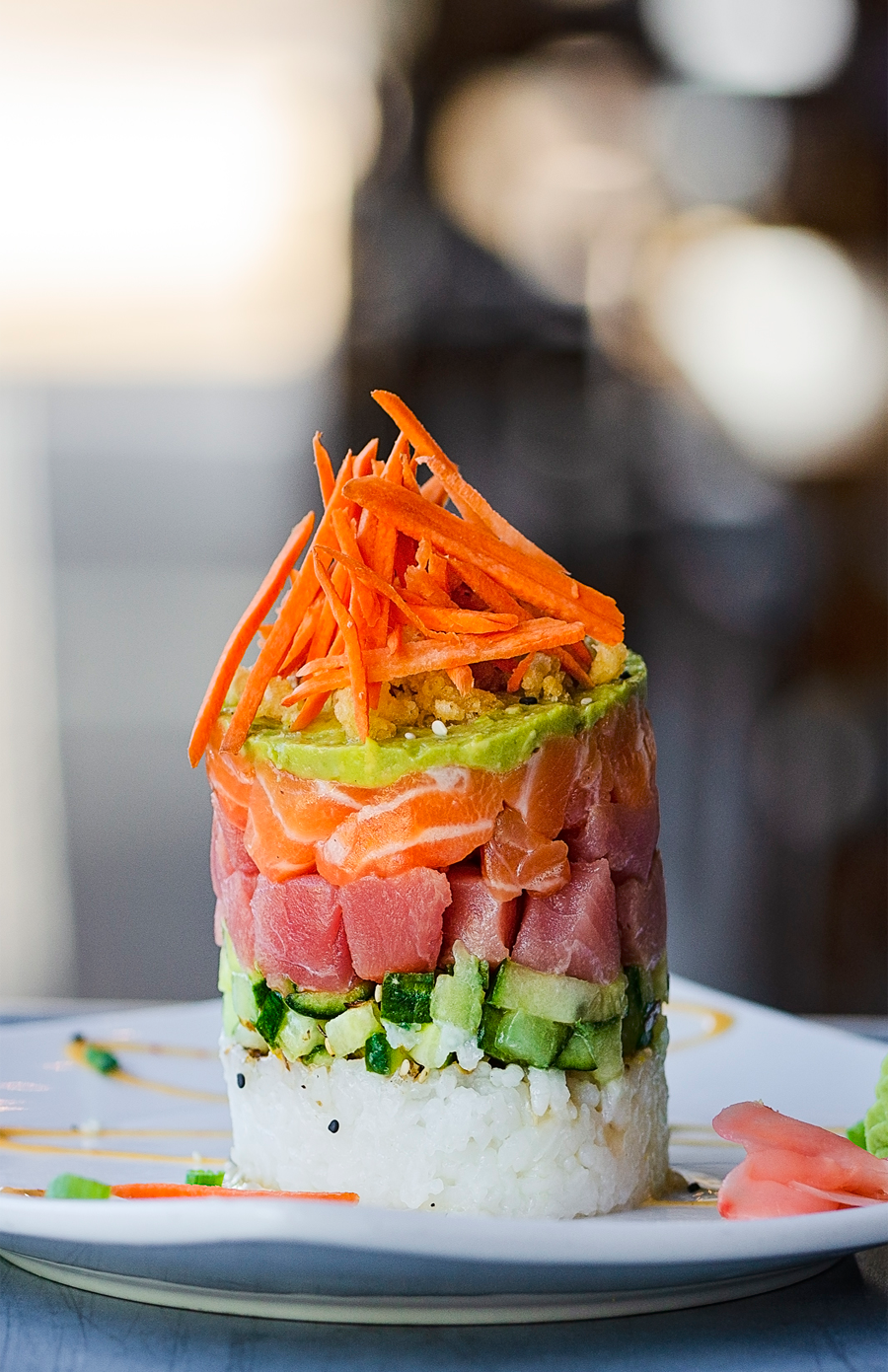 A white plate topped with a stack of sushi and vegetables.