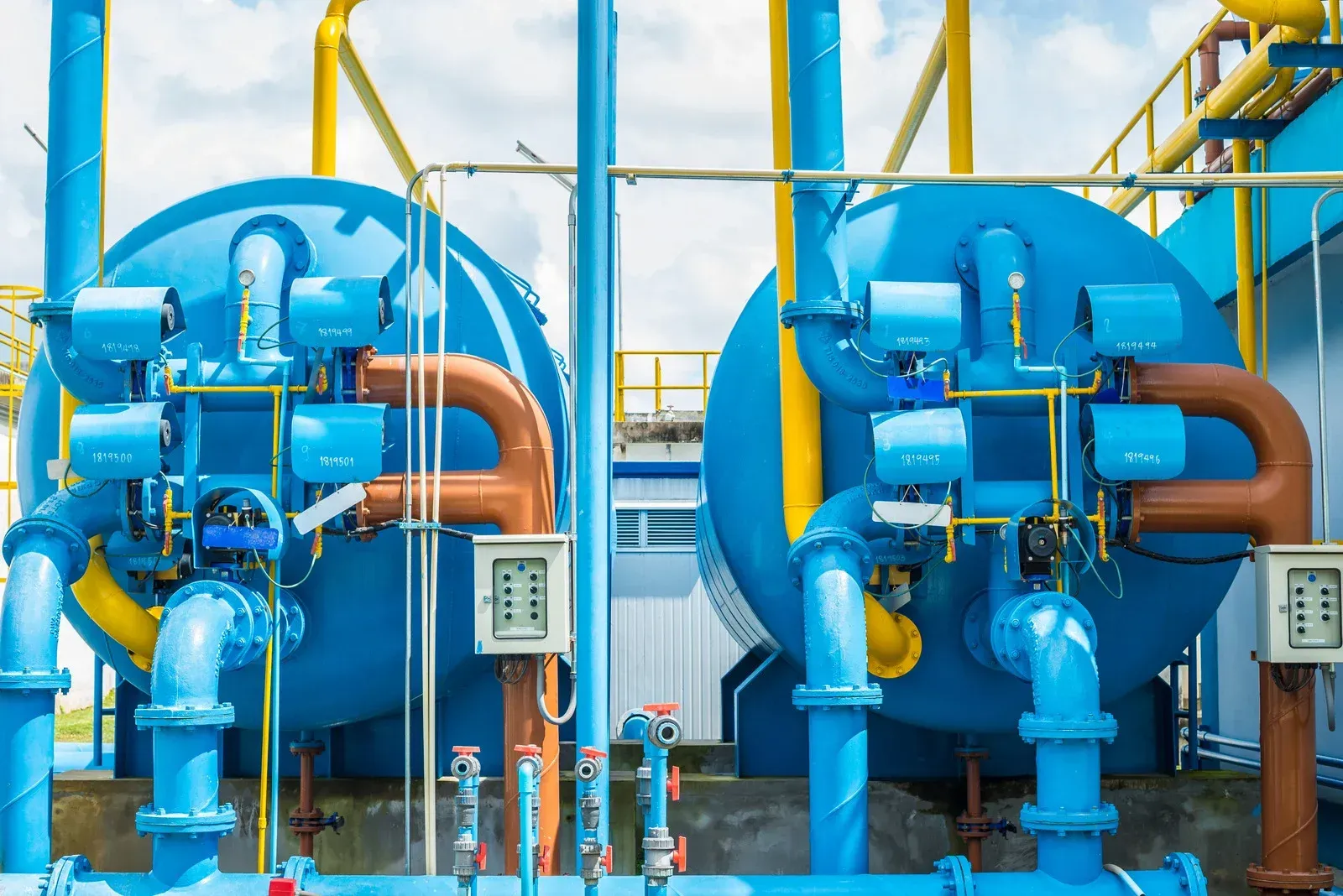 A row of blue pipes and valves in a factory.