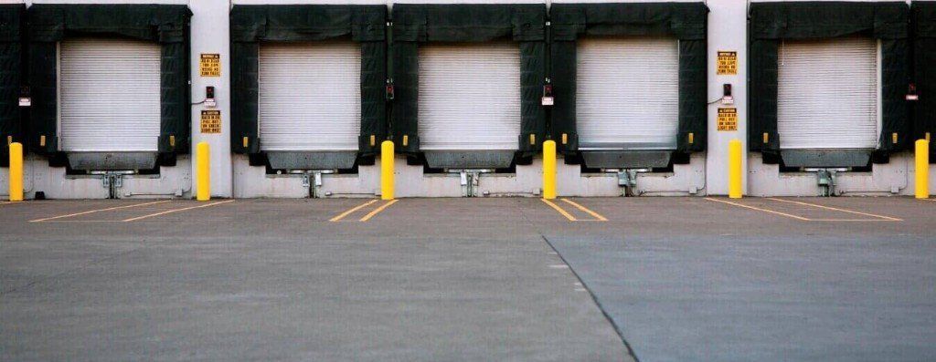 A row of loading docks are lined up in a parking lot.