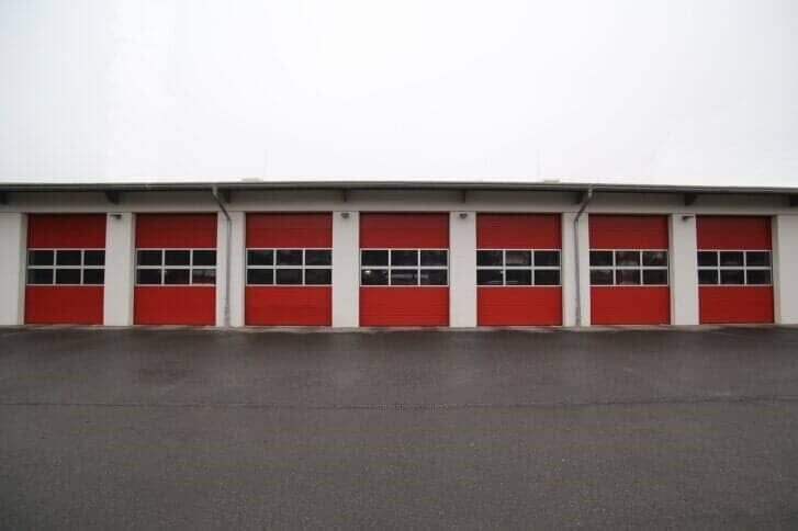 A row of red garage doors on a building.