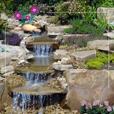 a waterfall surrounded by rocks and flowers in a garden