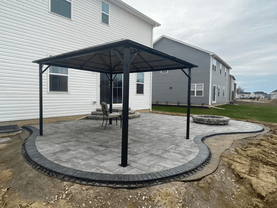 a patio with a gazebo and a fire pit in front of a house .