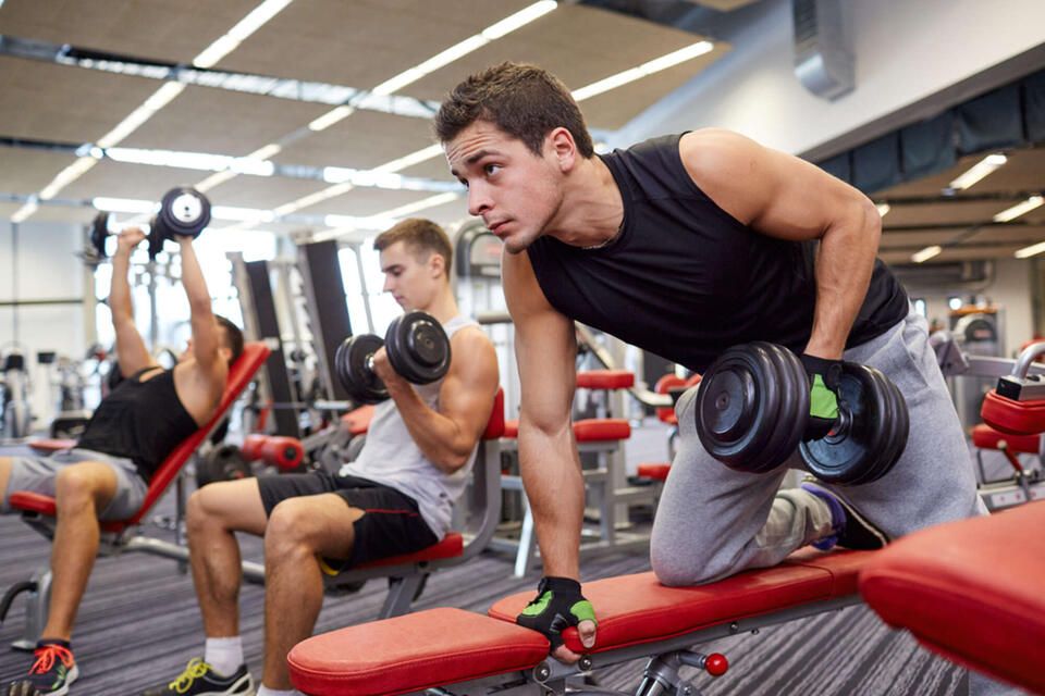 Three men are lifting dumbbells in a gym.
