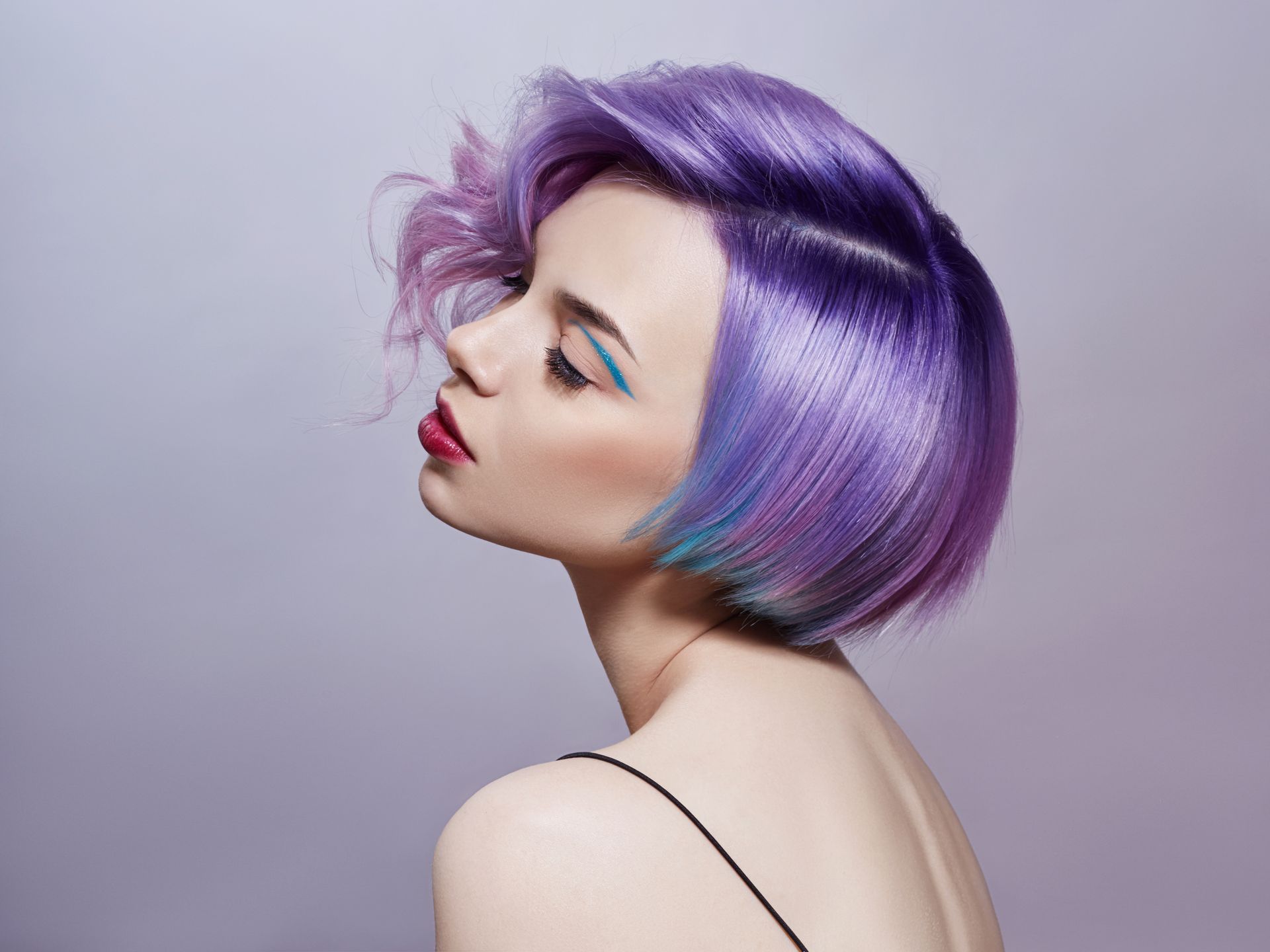 A woman with purple and blue hair is wearing a black tank top.
