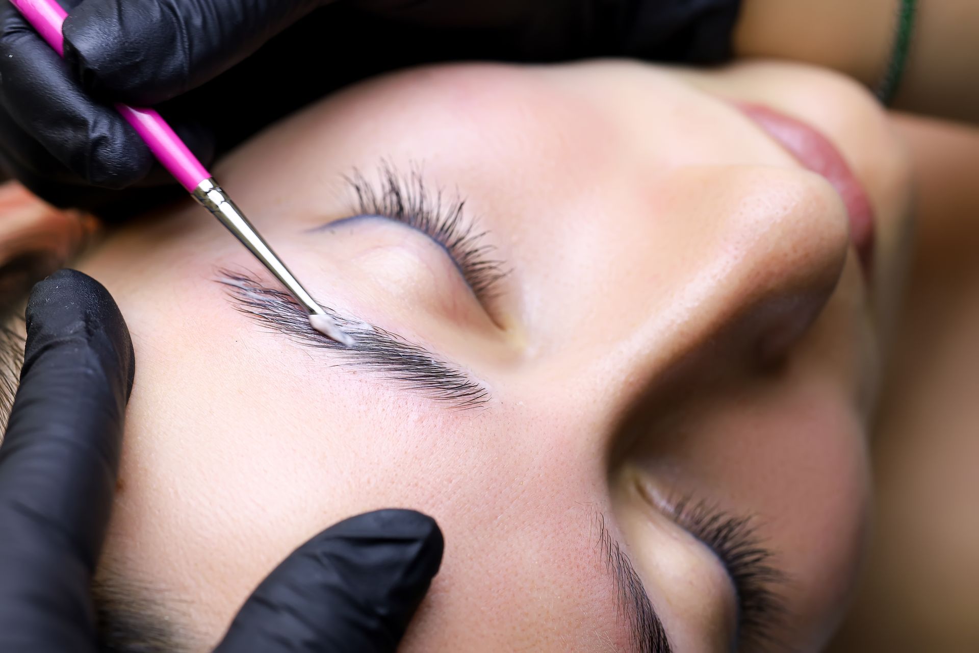 A woman is getting her eyebrows painted with a brush.