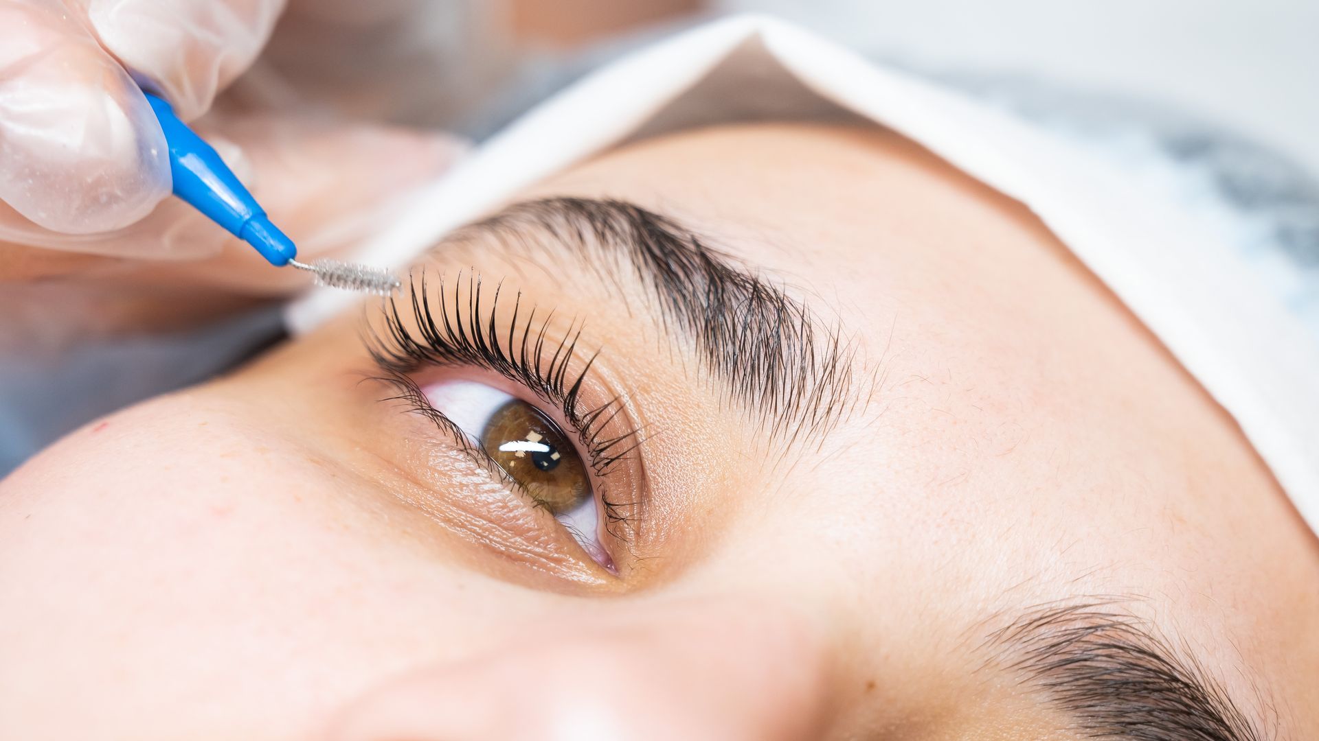 A woman is getting her eyebrows painted with a brush.