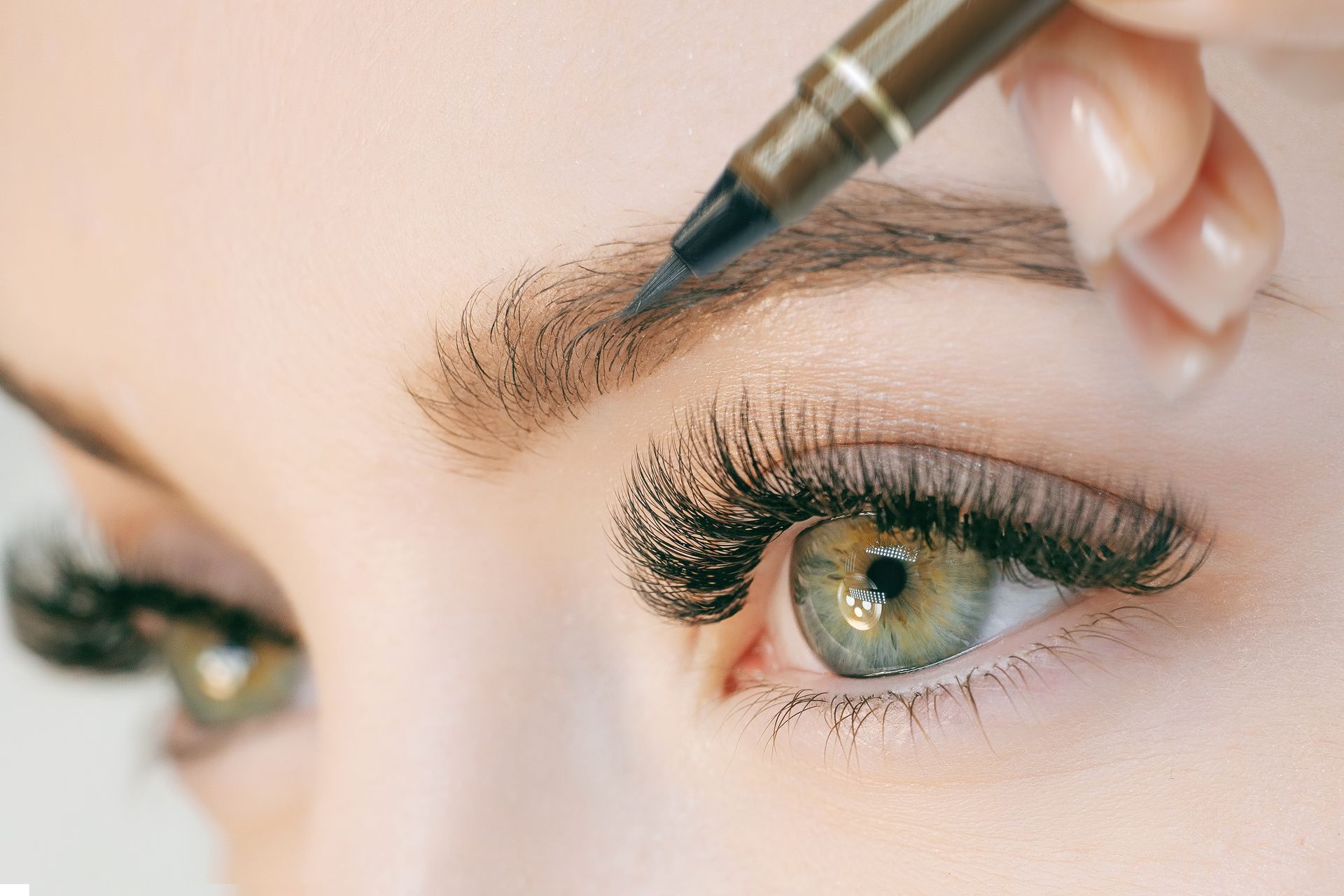 A woman is getting her eyebrows painted with a pen.