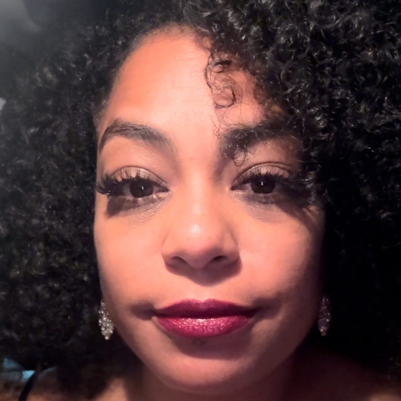 A woman in a black jacket and lace top smiles for the camera