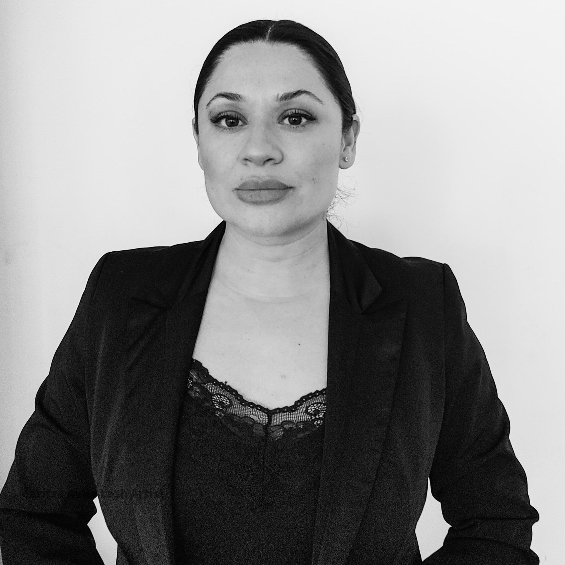 A woman in a black jacket and lace top smiles for the camera