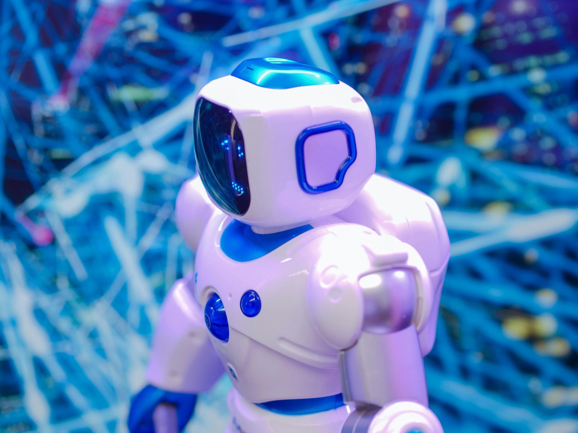 A white and blue robot is standing in front of a blue background.